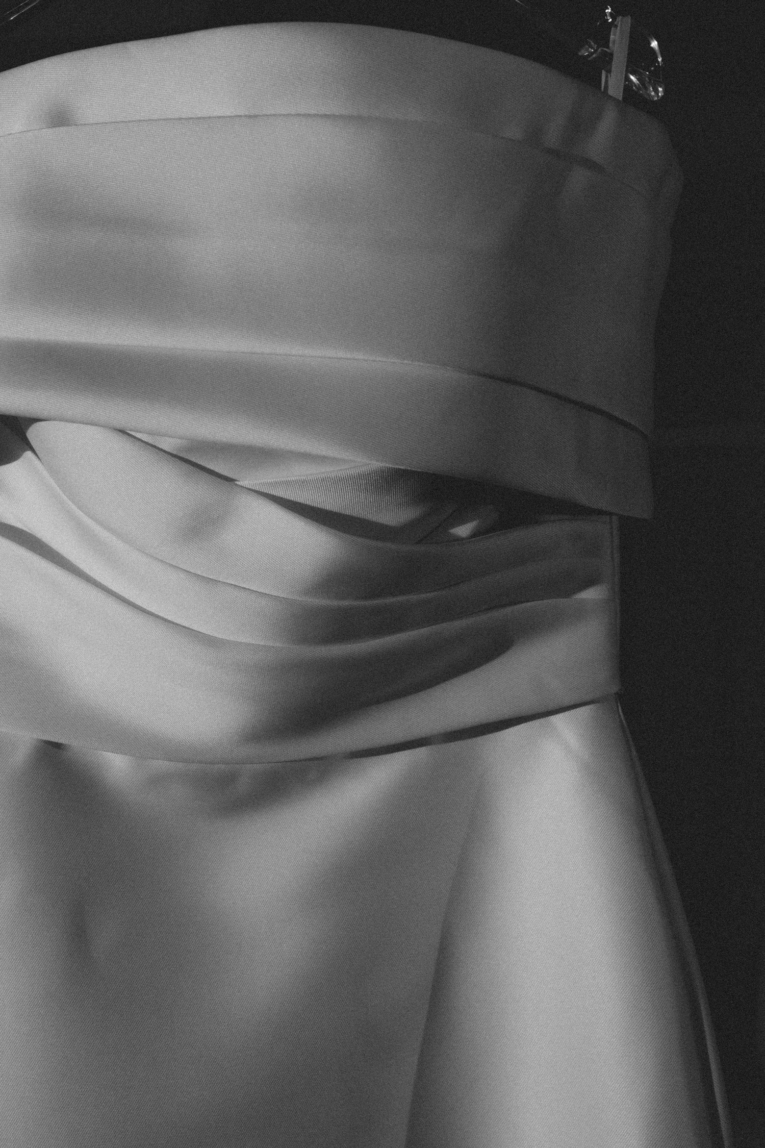 Black and white close-up of elegant satin wedding dress bodice detail.