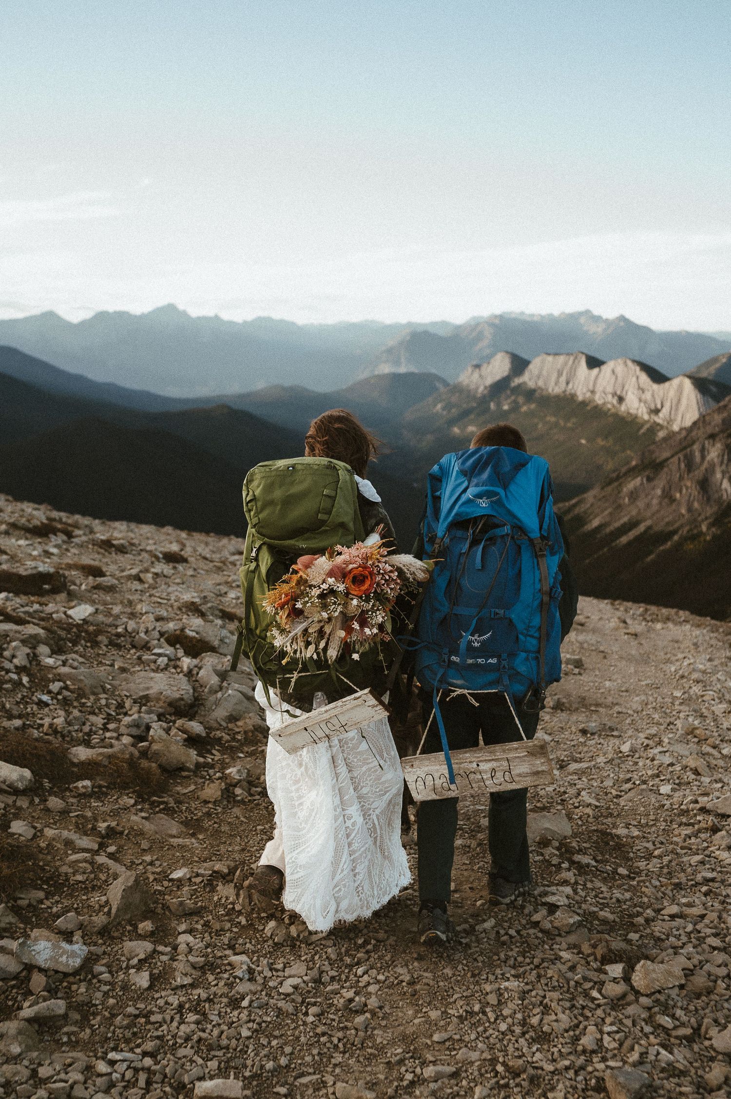 A romantic embrace between newlyweds with majestic mountain peaks as their backdrop.