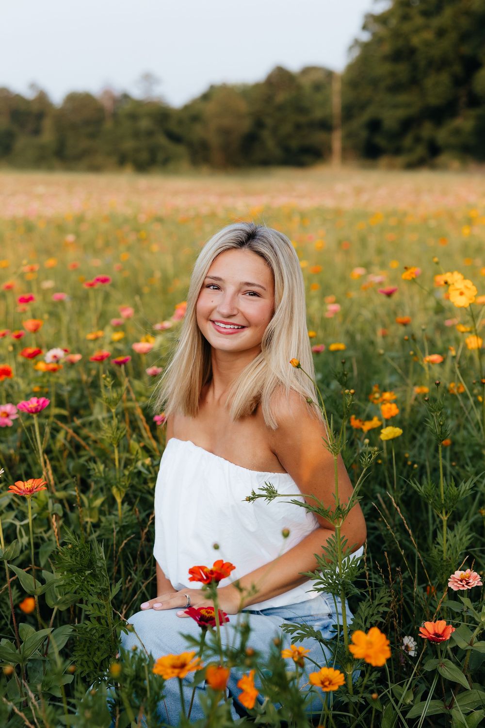 A person sits in a vibrant field of orange and red wildflowers on a sunny summer day.