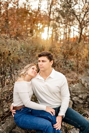 Couple in white and denim relaxing together during golden hour in an autumn setting.