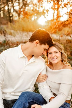 Candid moments between couple wearing coordinated white tops during autumn sunset photoshoot.