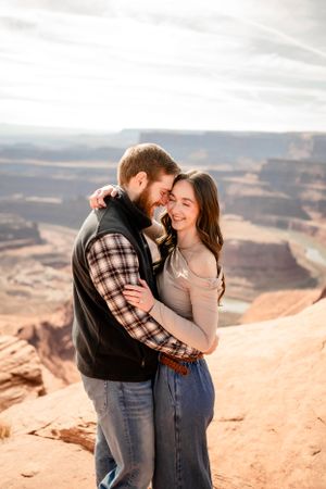 Intimate moment shared between couple against backdrop of sweeping canyon views.