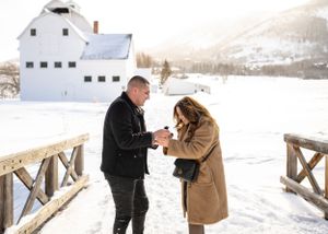 A romantic moment captured on a snowy wooden bridge during winter.