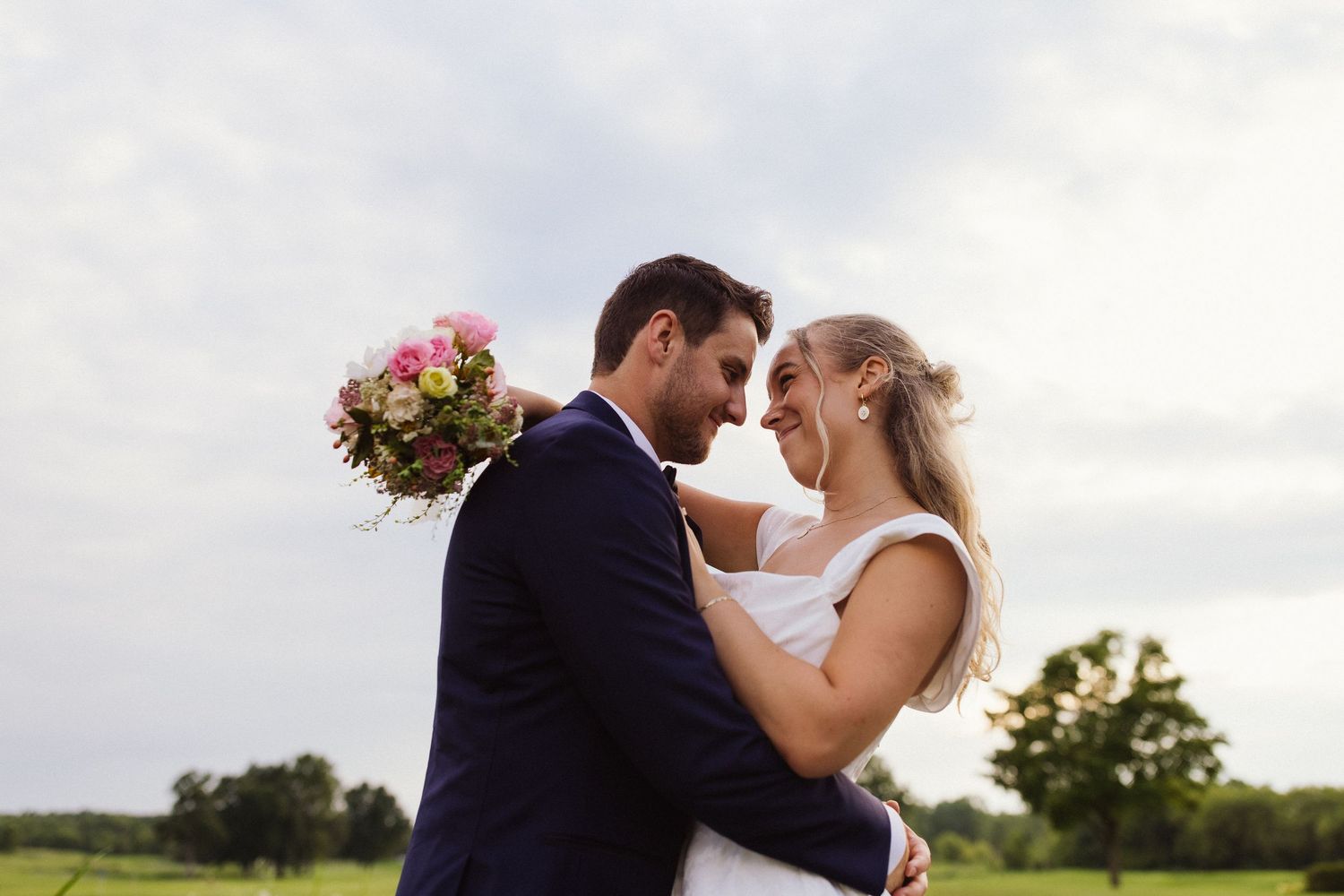 A wedding party shares a candid moment outdoors with nuns and a bride holding a bouquet.