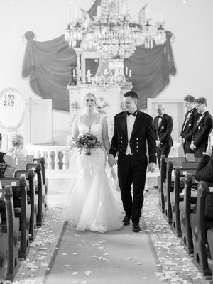 Black and white wedding ceremony montage shows ring bearer walking down church aisle adorned with flower petals.