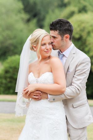 A wedding couple embraces outdoors in a romantic series of poses against a lush green background.