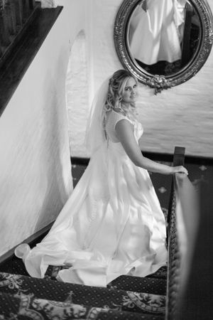 Black and white bridal portrait showing a flowing wedding gown next to an ornate mirror.