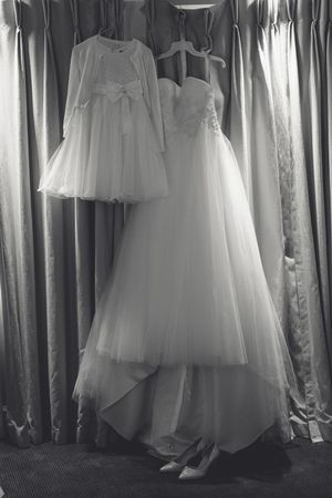 Two elegant white wedding dresses hanging side by side - a full-length gown and a shorter dress with tulle skirts.