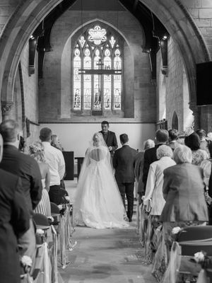 A black and white wedding ceremony sequence showing rows of guests and stained glass windows in a church setting.