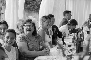 Candid black and white photo of guests enjoying themselves at a wedding reception party.