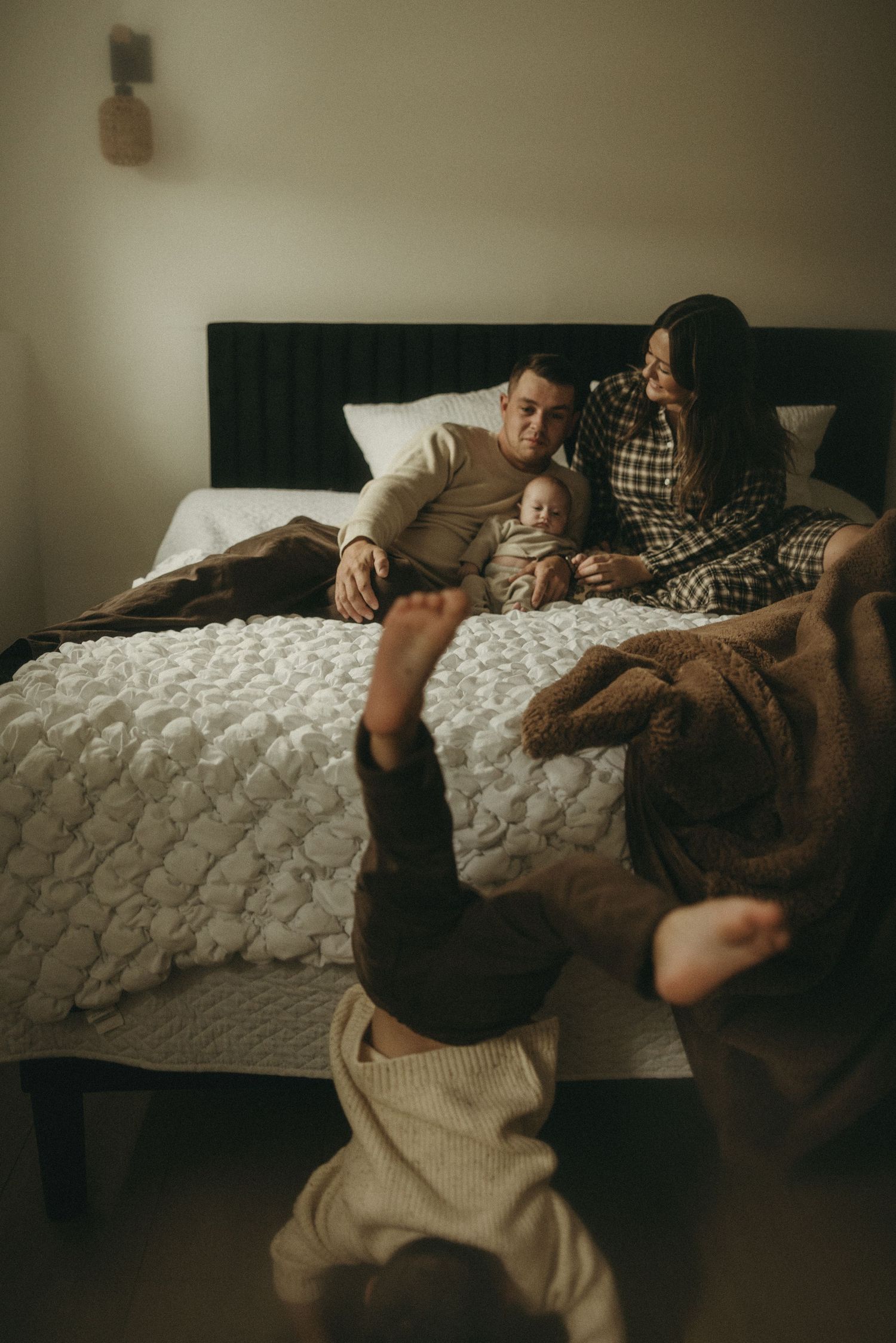 Two people share a playful moment while relaxing together on a quilted bed.
