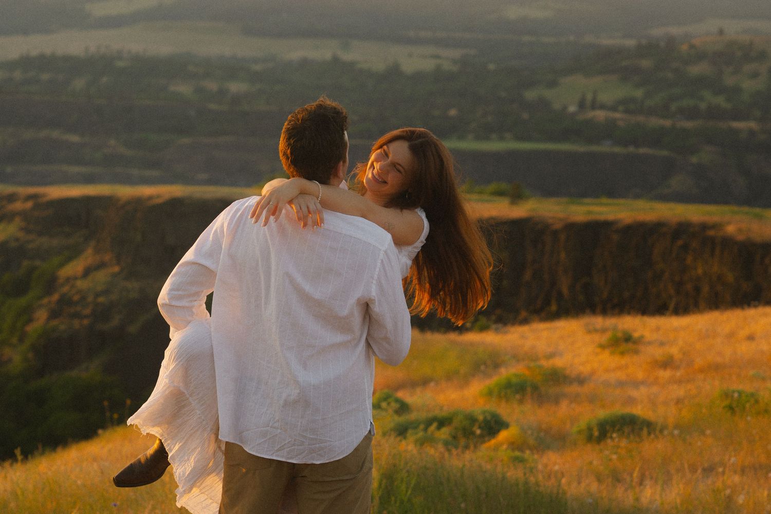 A joyful moment captured in front of a tall cascading waterfall surrounded by lush forest.