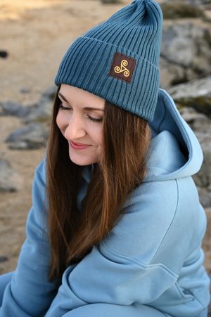 Winter fashion scene featuring blue beanie with logo patch and matching hoodie.