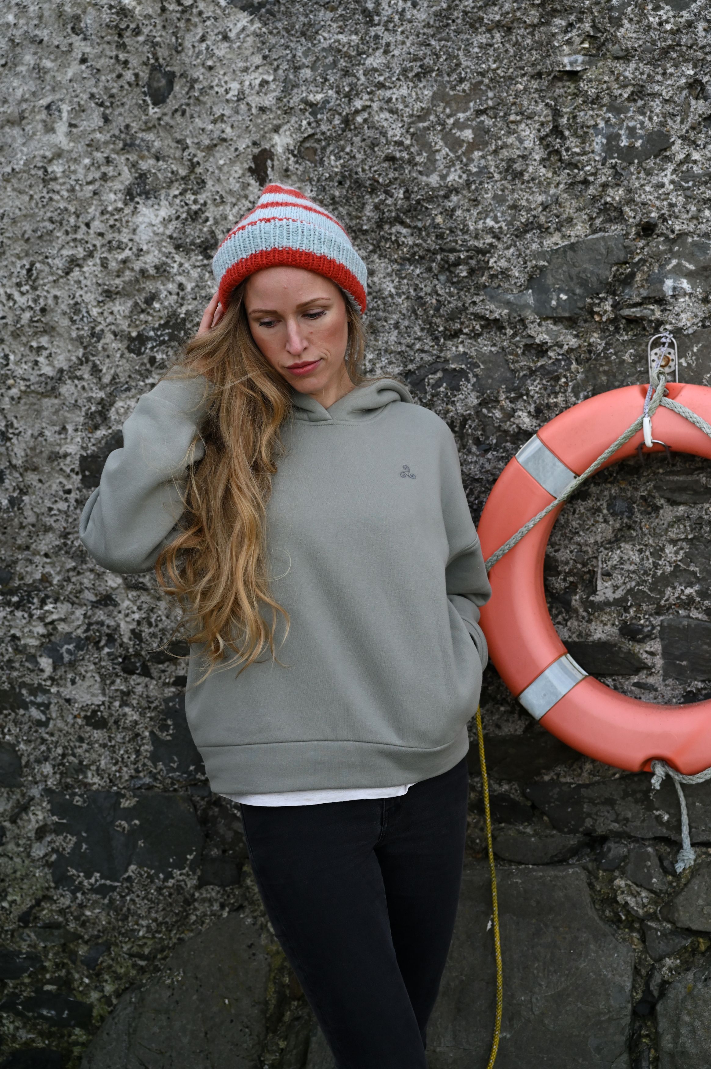 Casual lifestyle portrait against a stone wall with red sweater and natural lighting.