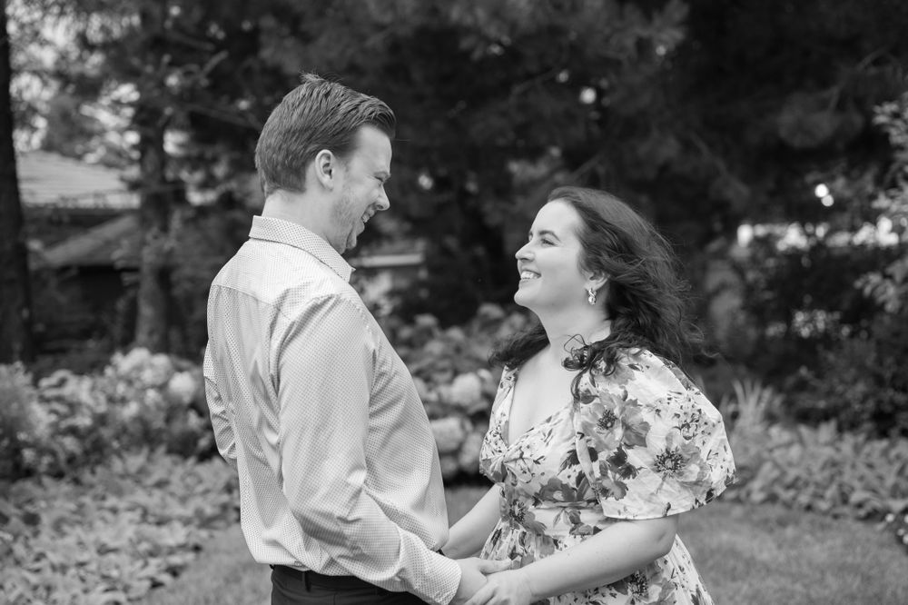 A couple shares a romantic engagement proposal on Toronto Island, with the iconic CN Tower and city skyline creating a stunning backdrop.
