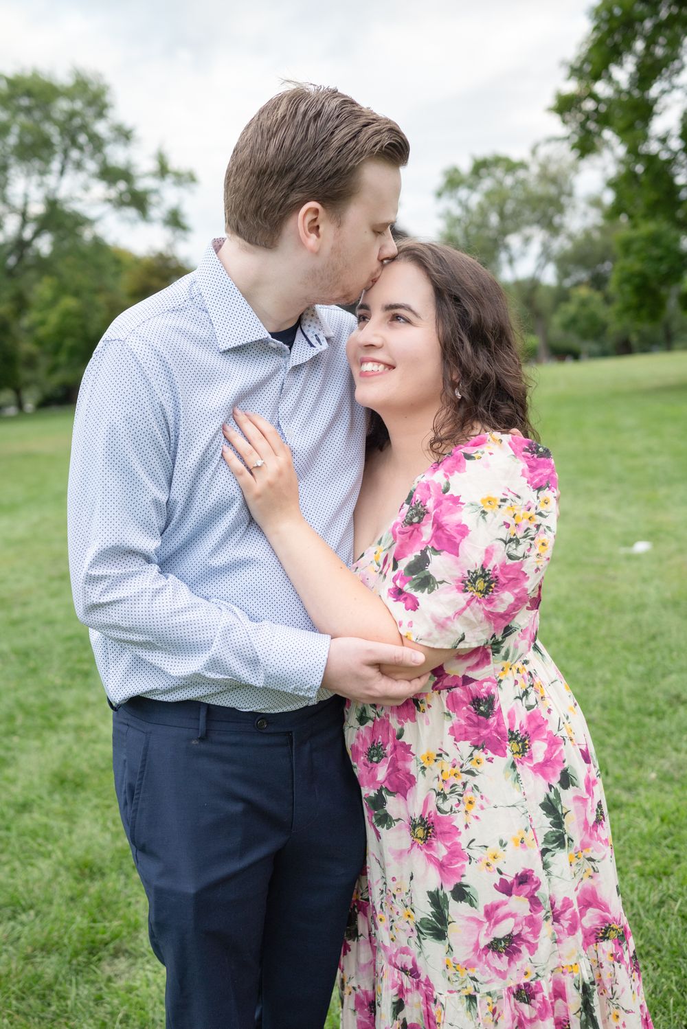 A couple shares a romantic engagement proposal on Toronto Island, with the iconic CN Tower and city skyline creating a stunning backdrop.