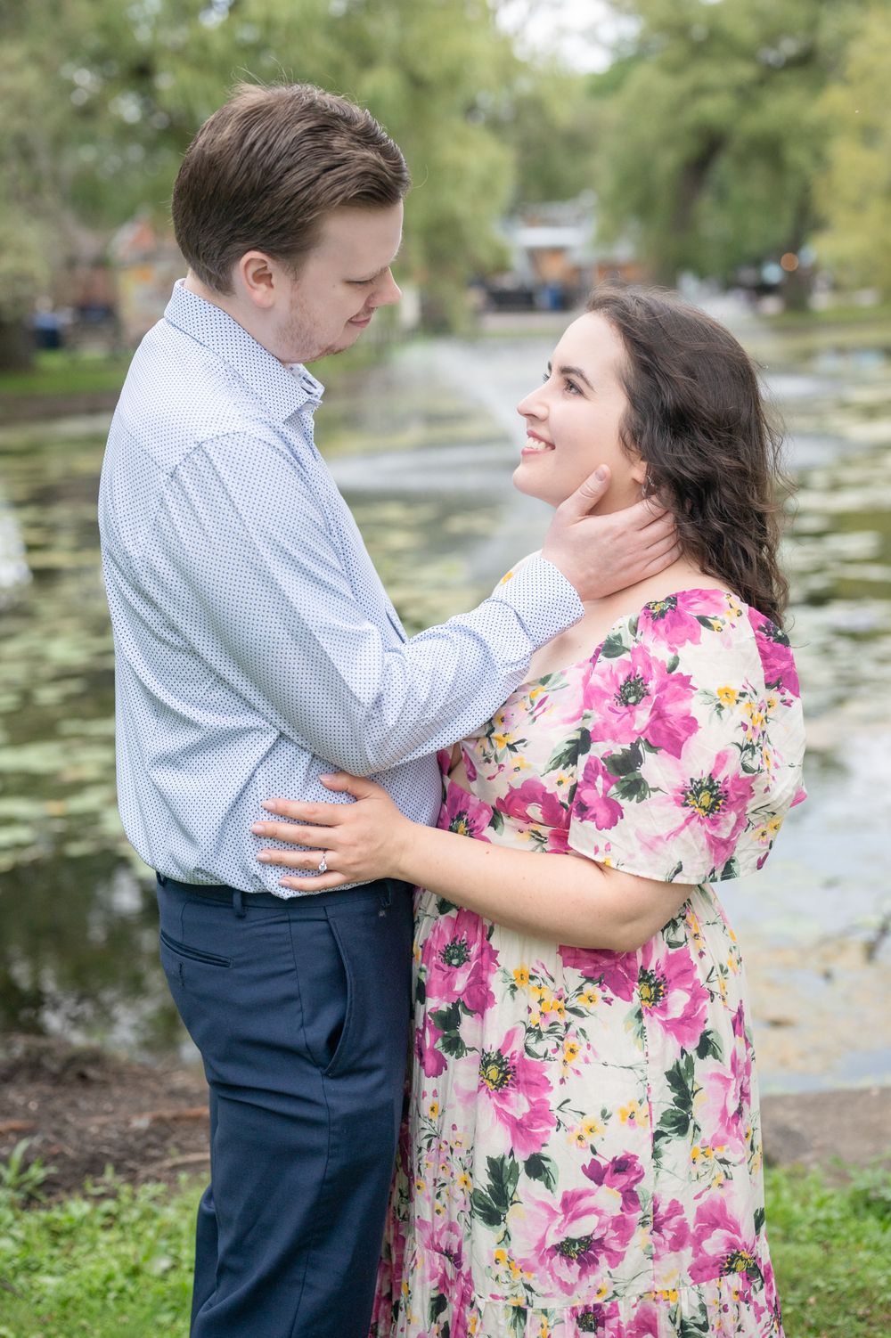 A couple shares a romantic engagement proposal on Toronto Island, with the iconic CN Tower and city skyline creating a stunning backdrop.