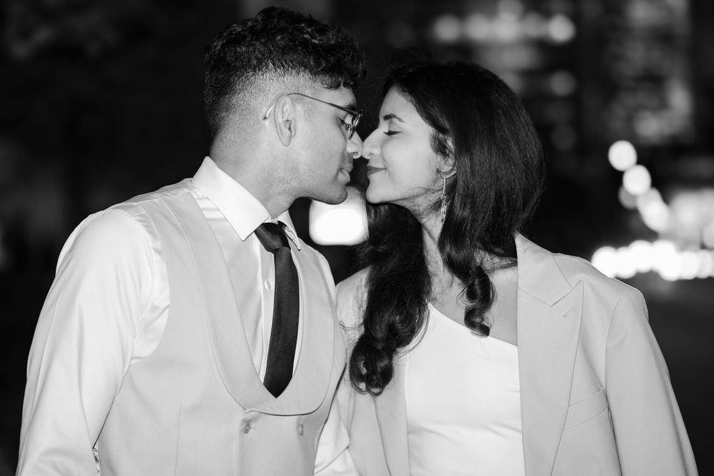 A romantic black and white photo of a couple sharing an intimate moment in formal attire at night.
