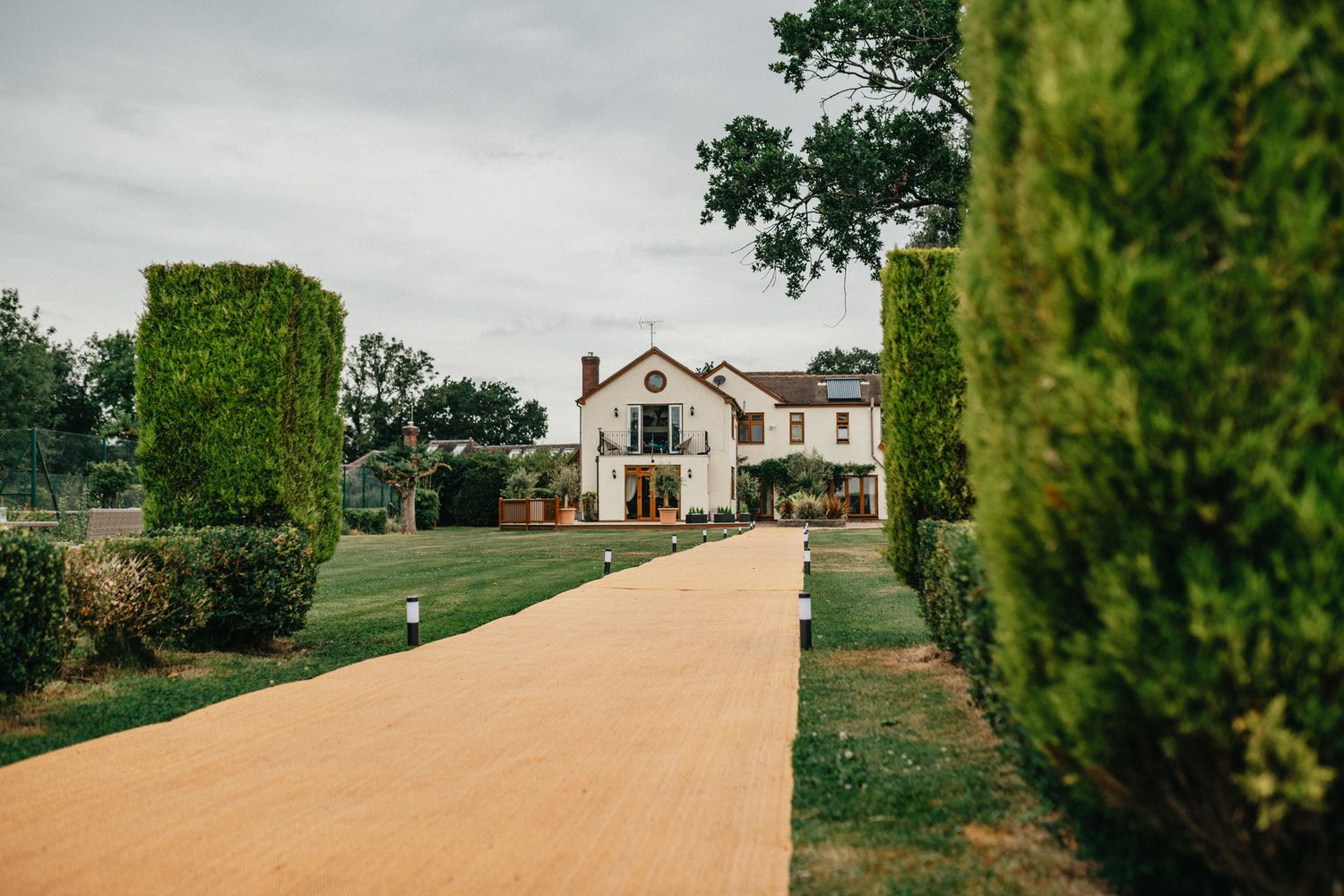 Elegant white mansion with ivy-covered walls and a beige pathway leading to the entrance.