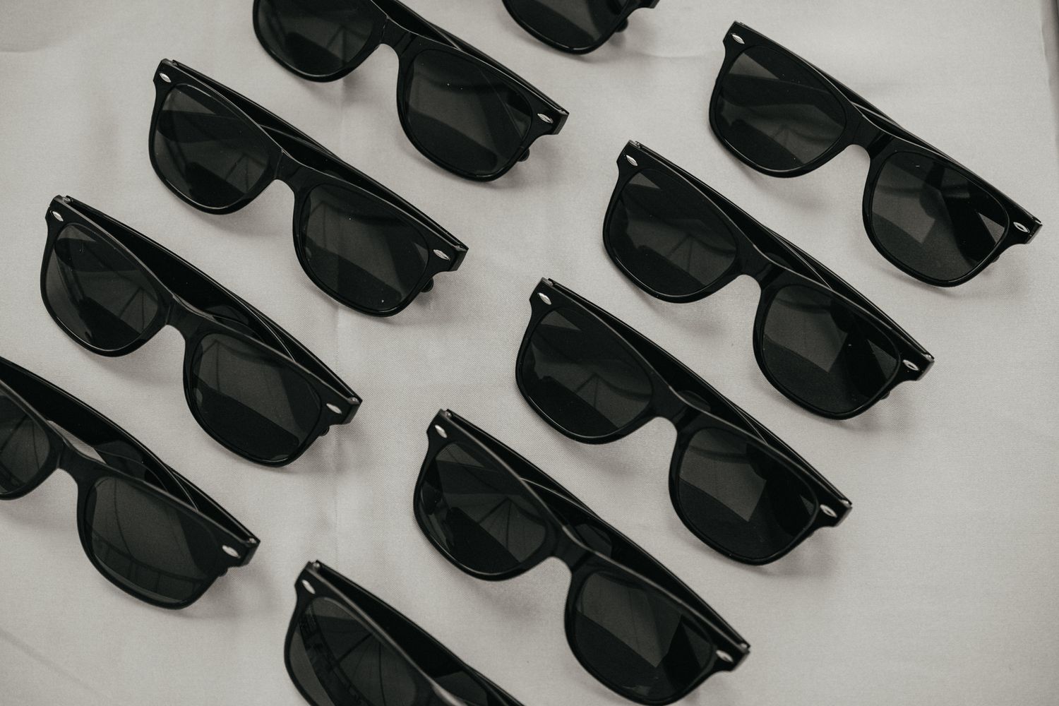 Collection of matching black sunglasses arranged in neat rows.
