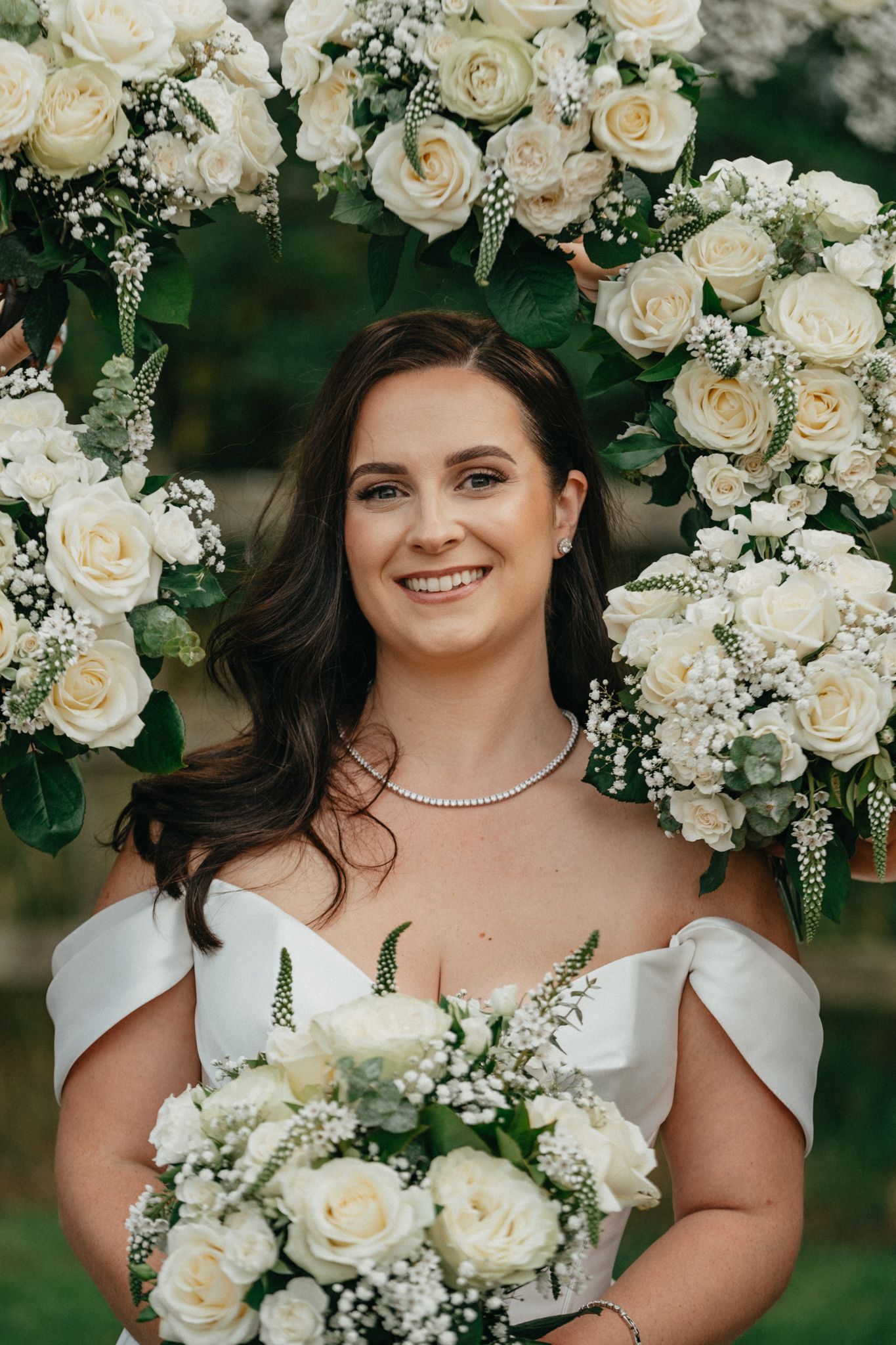 White roses and baby's breath create elegant floral arch backdrop.