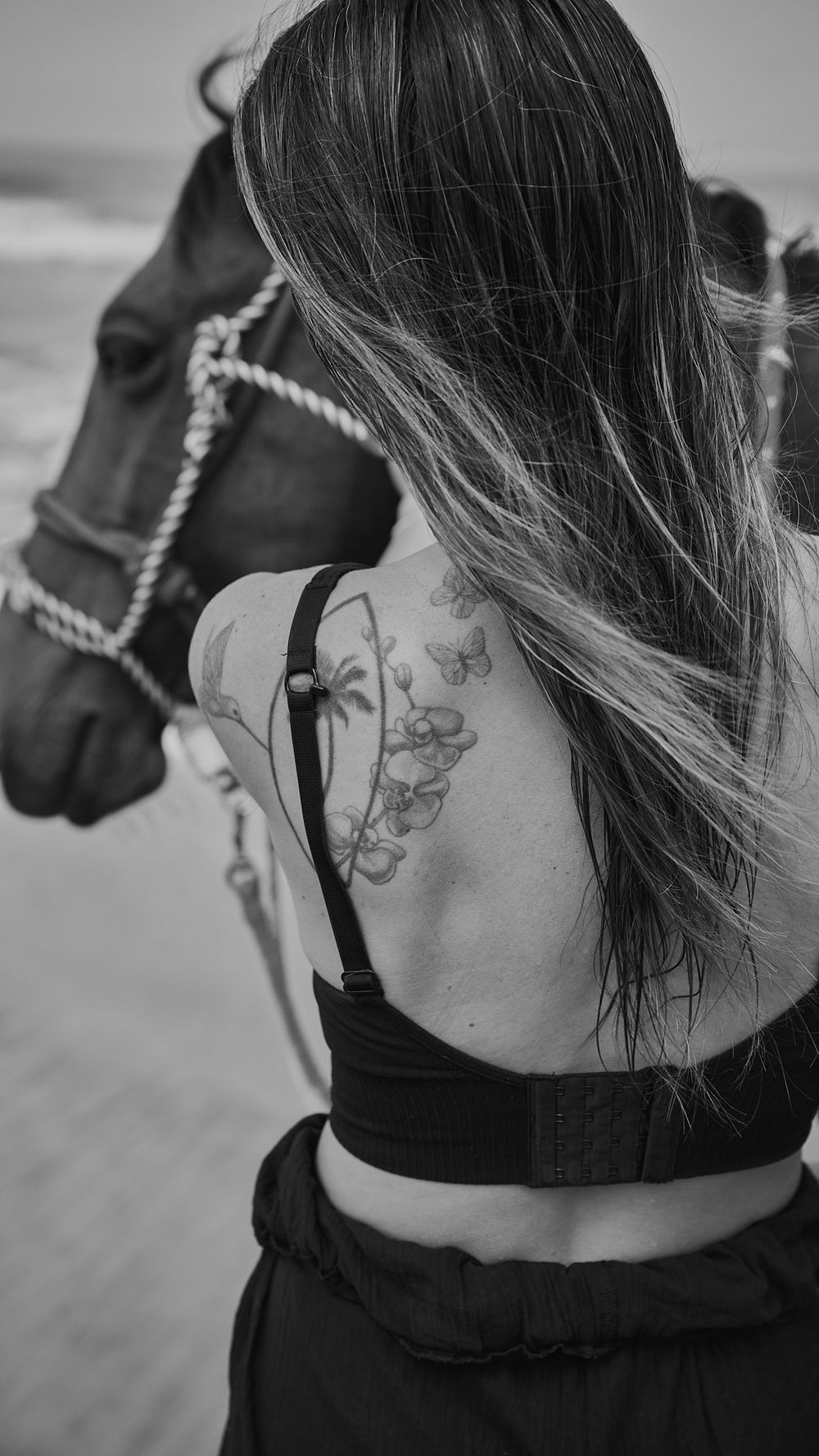 Black and white close-up of a delicate butterfly tattoo on someone's neck, shown from multiple angles.