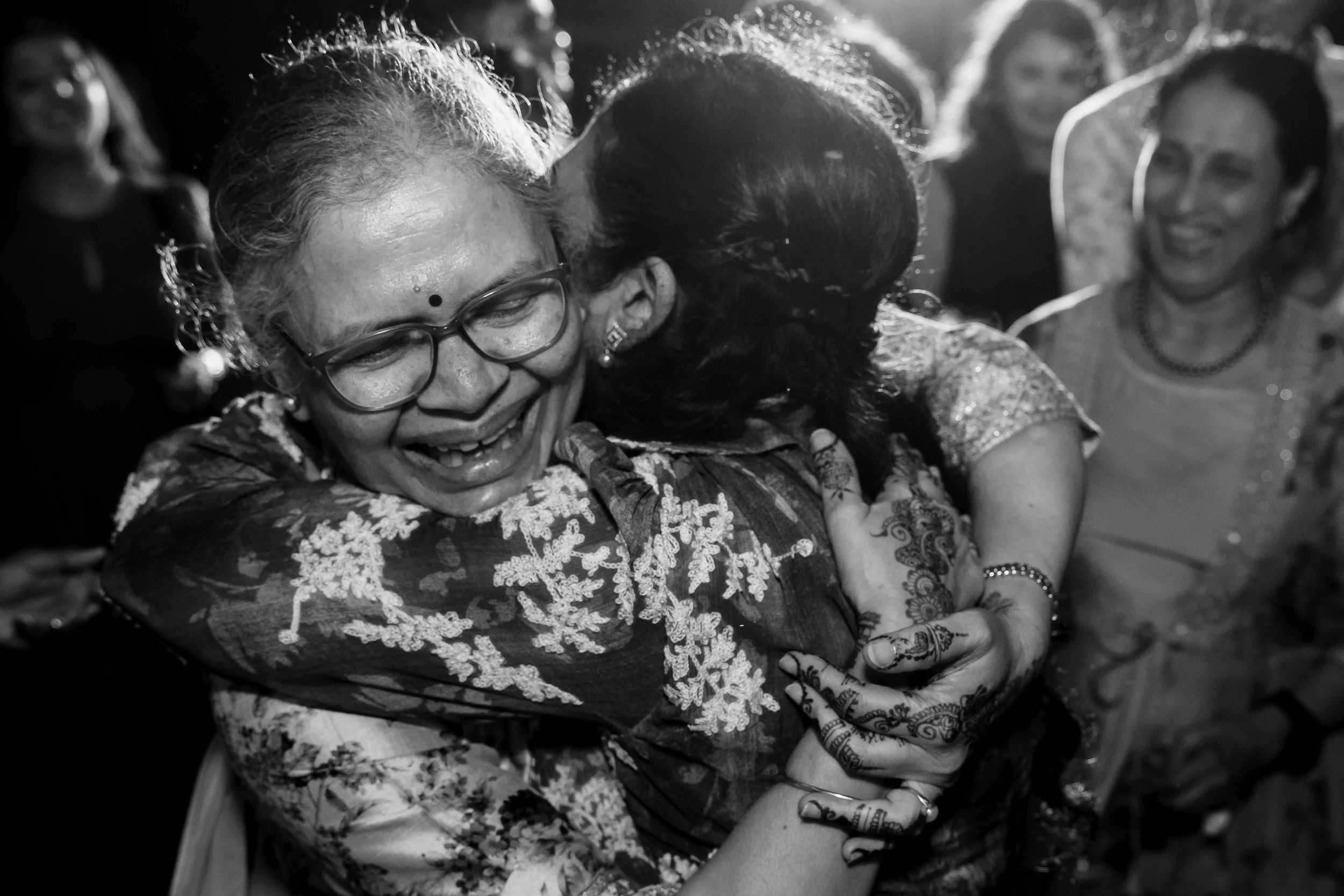 A heartfelt embrace captured in black and white as two people share an emotional moment at a gathering.