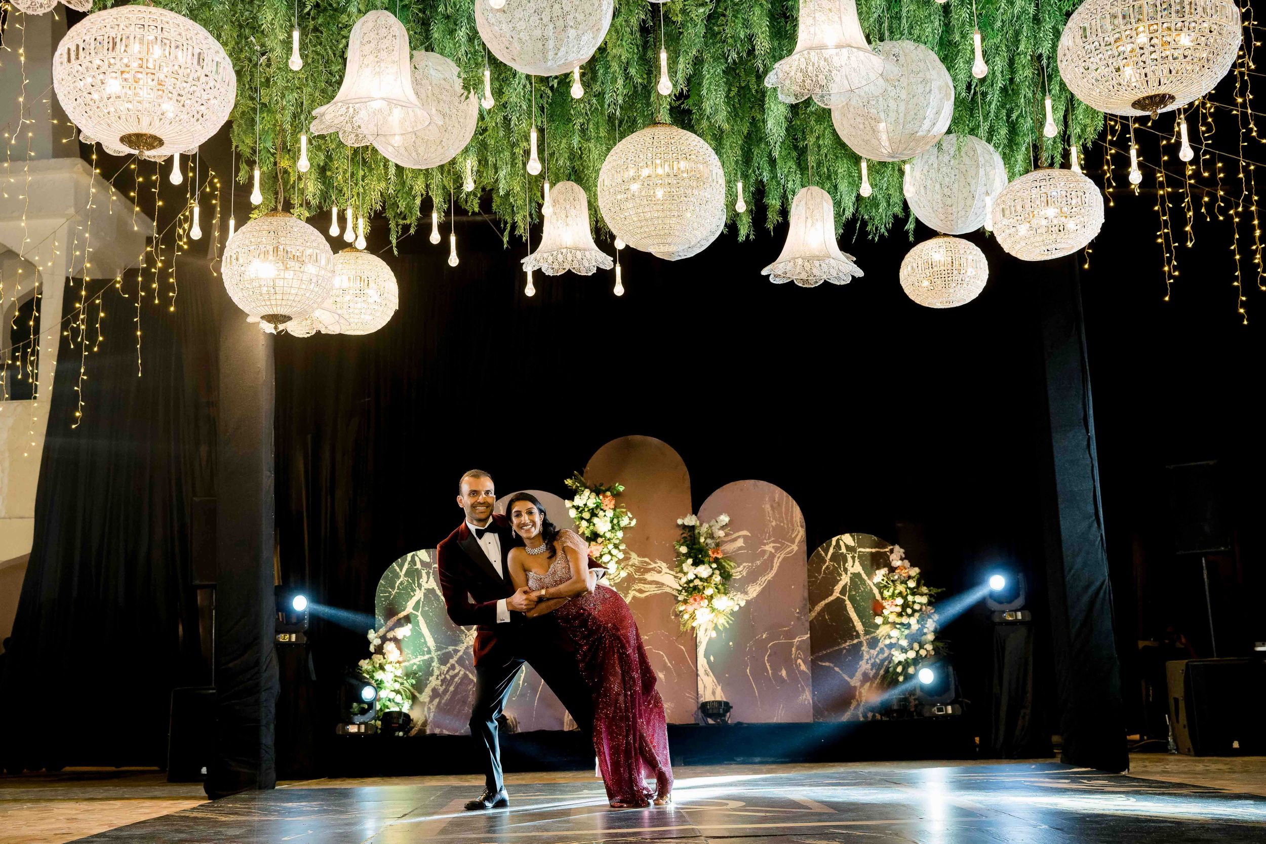 Crystal chandeliers and paper lanterns create a magical ambiance at an elegant evening wedding reception.