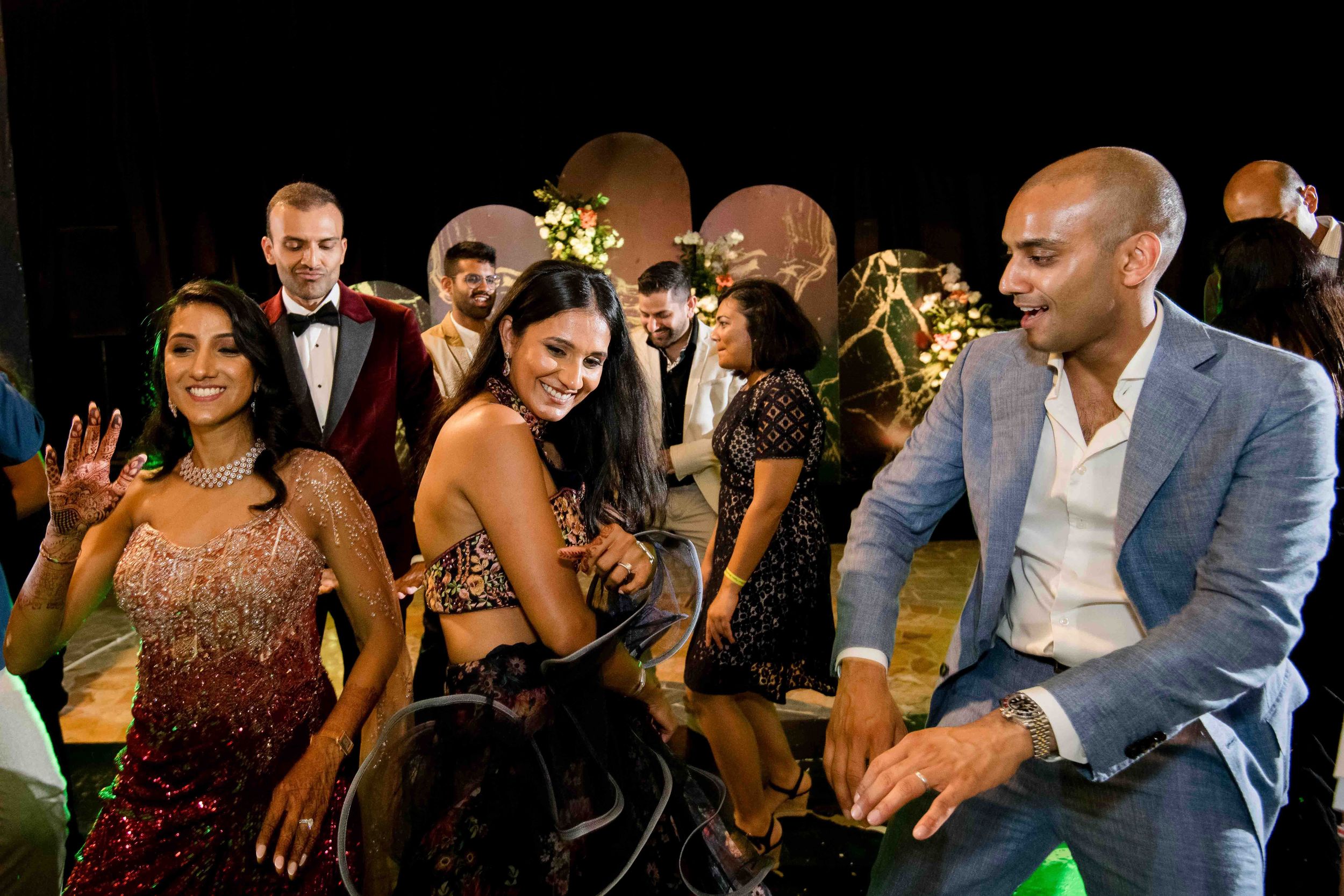 People dance and celebrate at an elegant formal event wearing evening attire and suits.