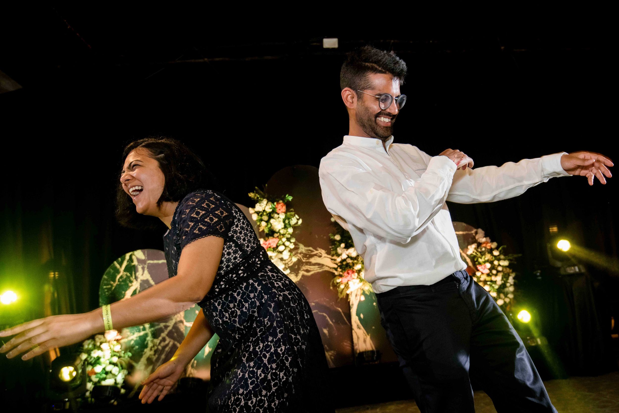 Couples dancing together at a nighttime outdoor wedding reception with glowing lights in the background.