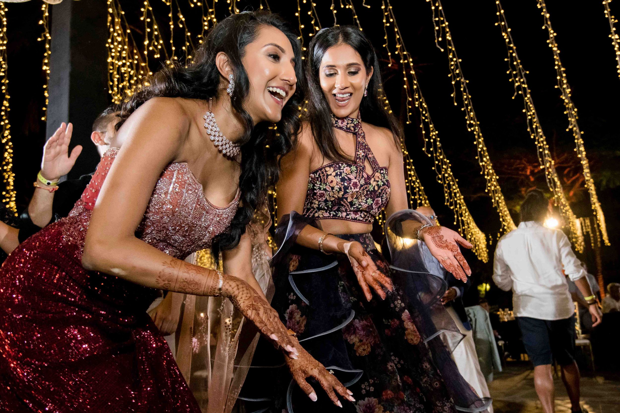 Party guests enjoying themselves on a dance floor with decorative string lights glowing above them.