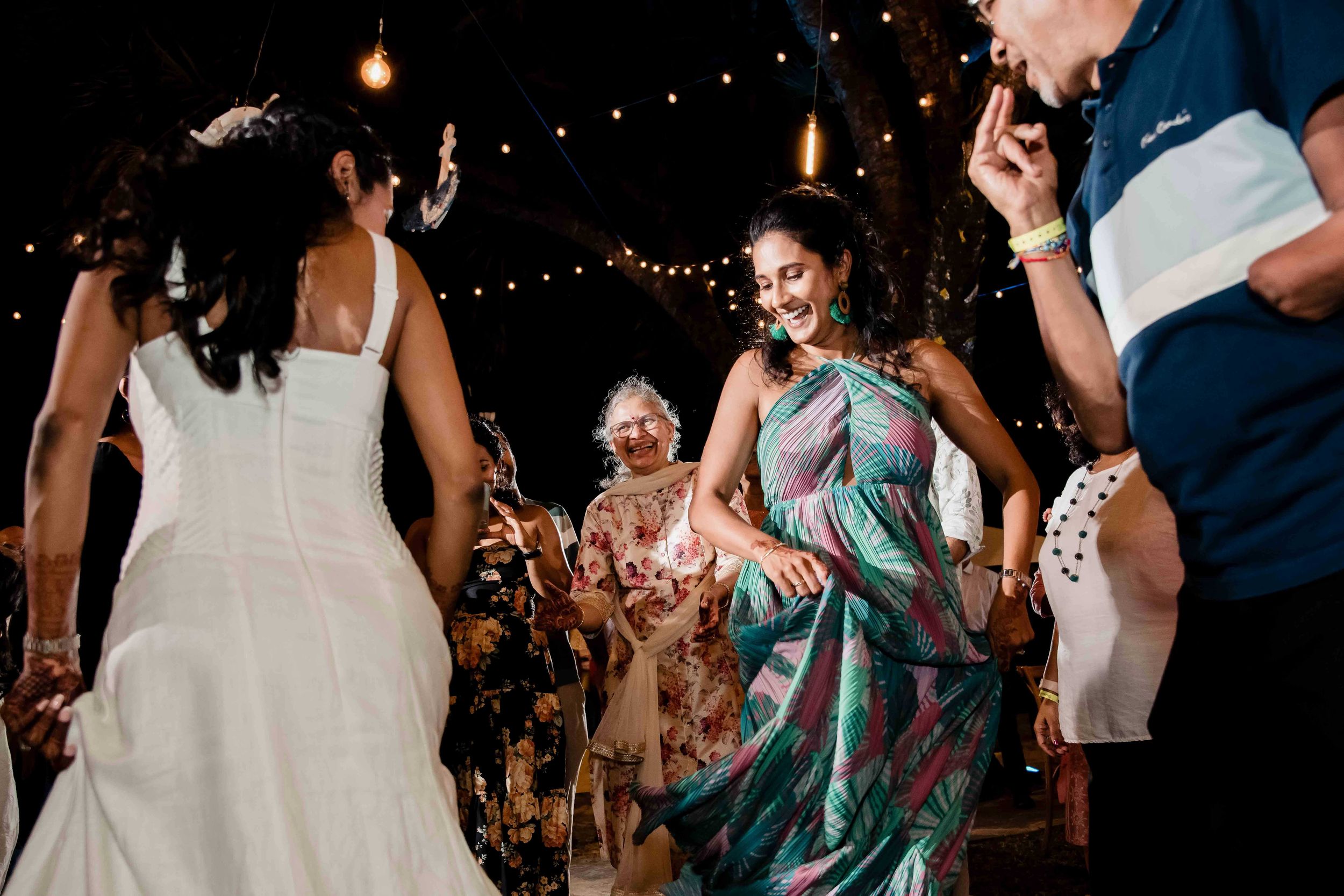 Wedding reception dance floor filled with guests celebrating under twinkling lights during evening festivities.