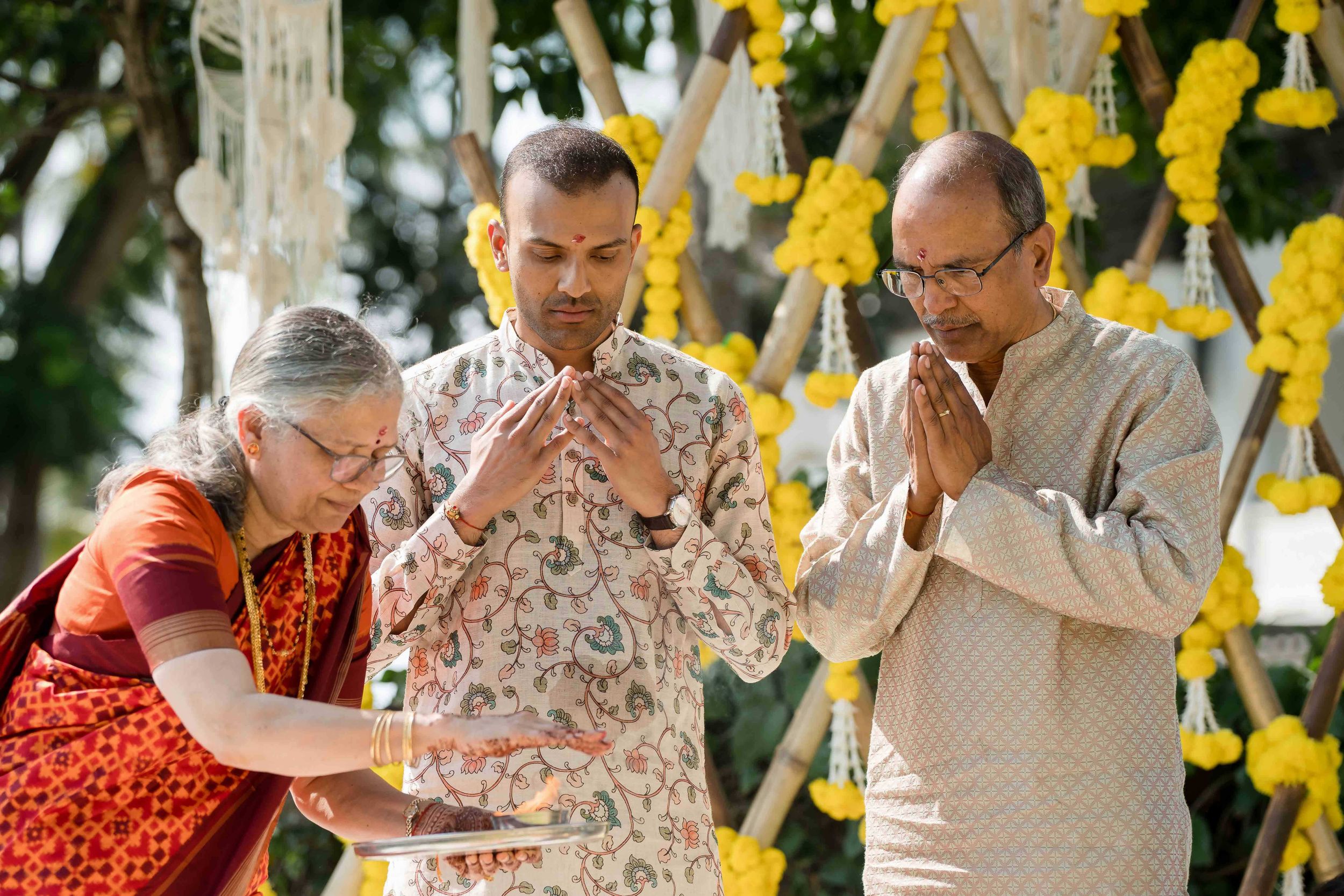 Group of people seated at outdoor venue with yellow floral decorations enjoying a festive celebration.