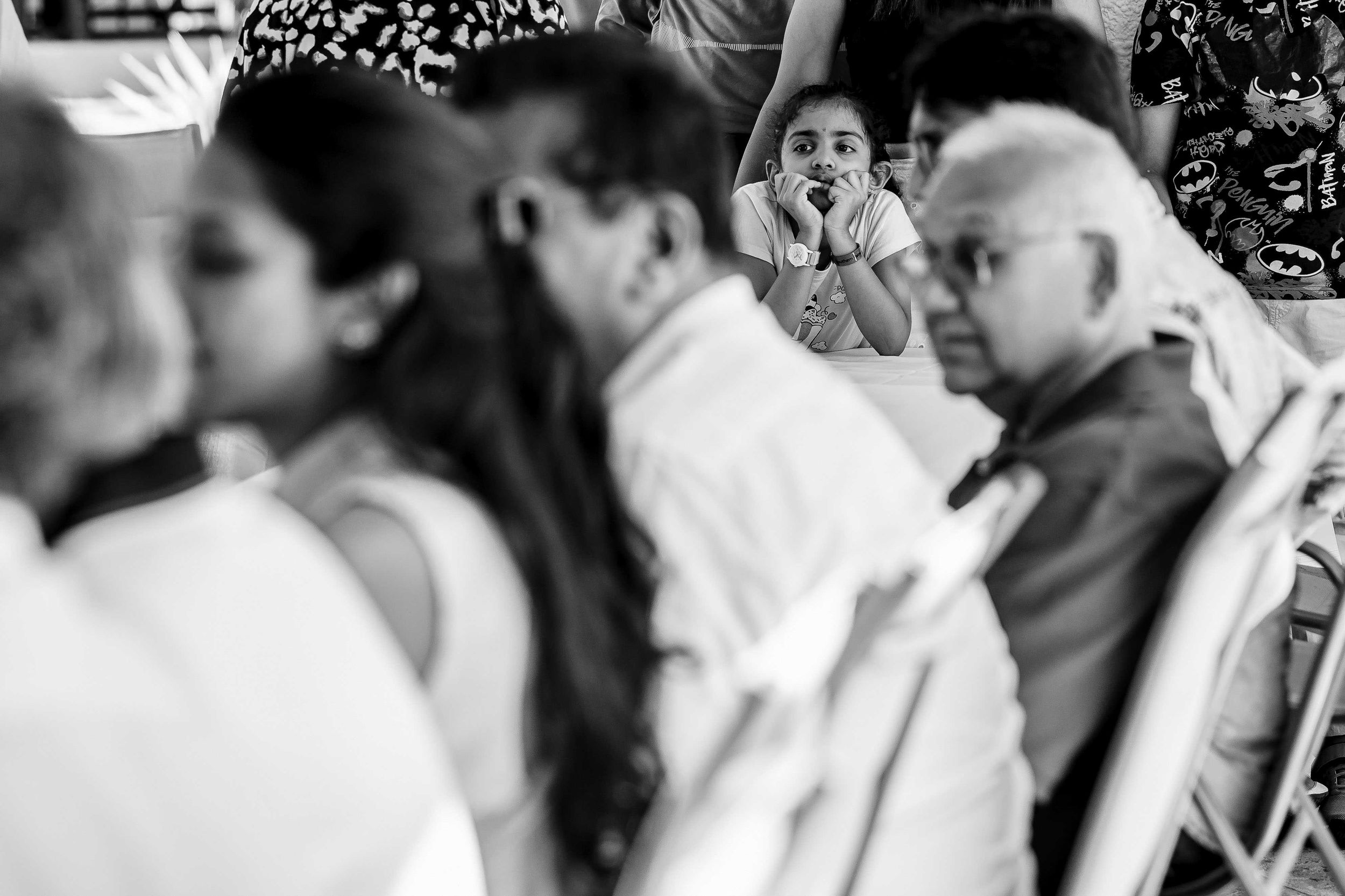 A black and white photograph shows a crowd of people in formal attire dancing at an elegant event hall.