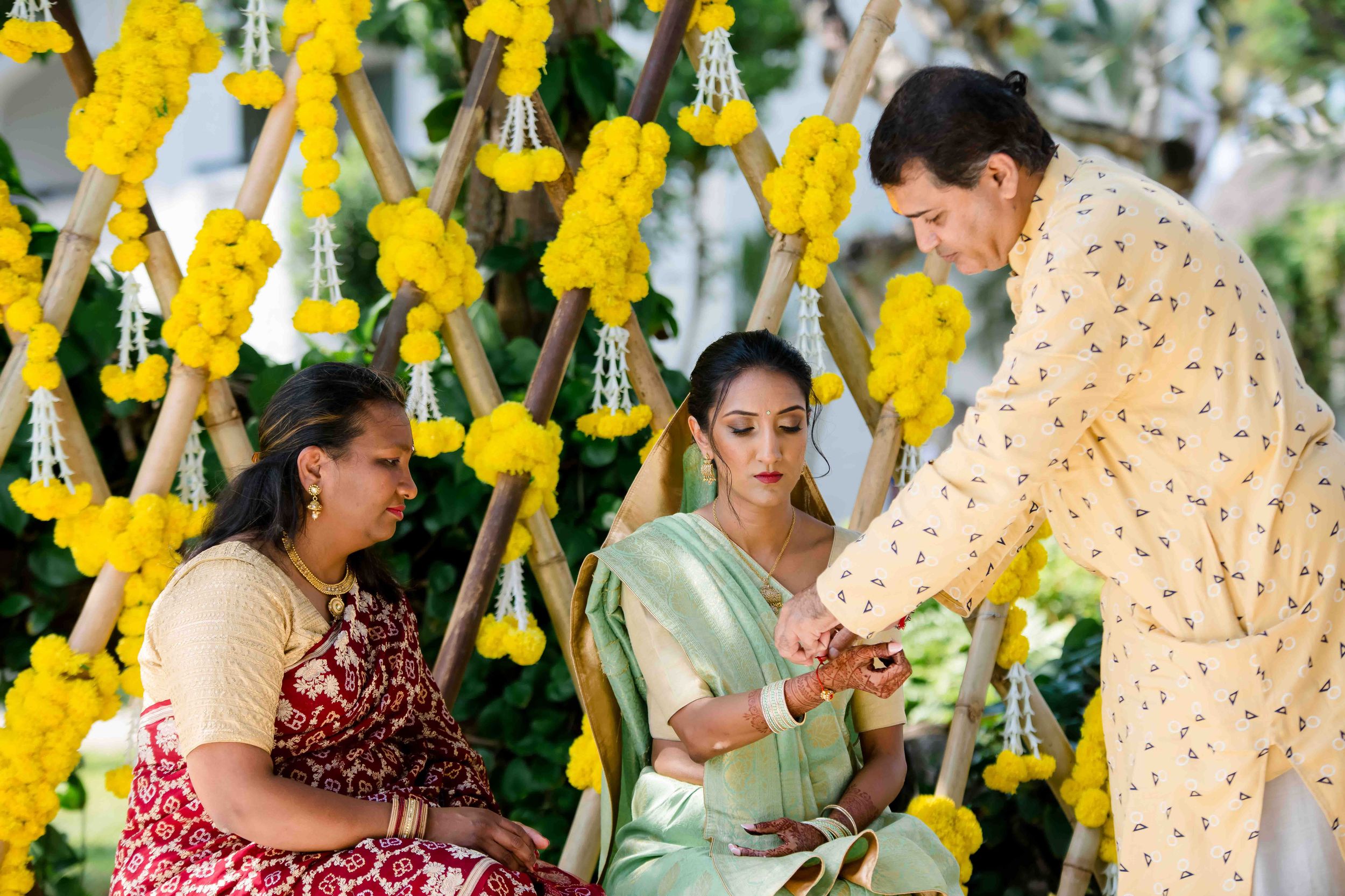 Group of people celebrating with vibrant yellow floral decorations hanging at a festive outdoor event.