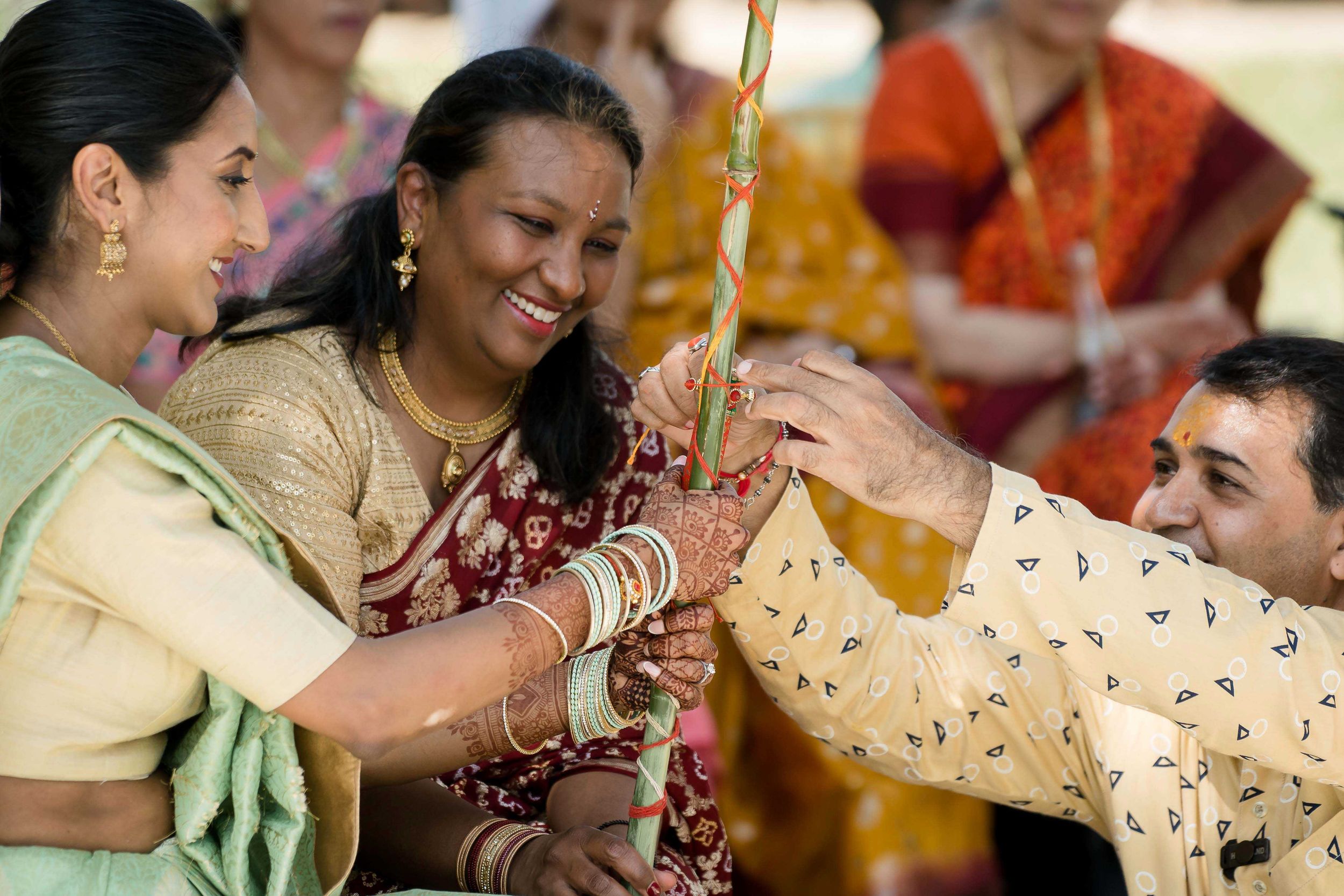 Traditional Hindu pre-wedding ritual with guests pouring water during a joyous ceremonial moment.