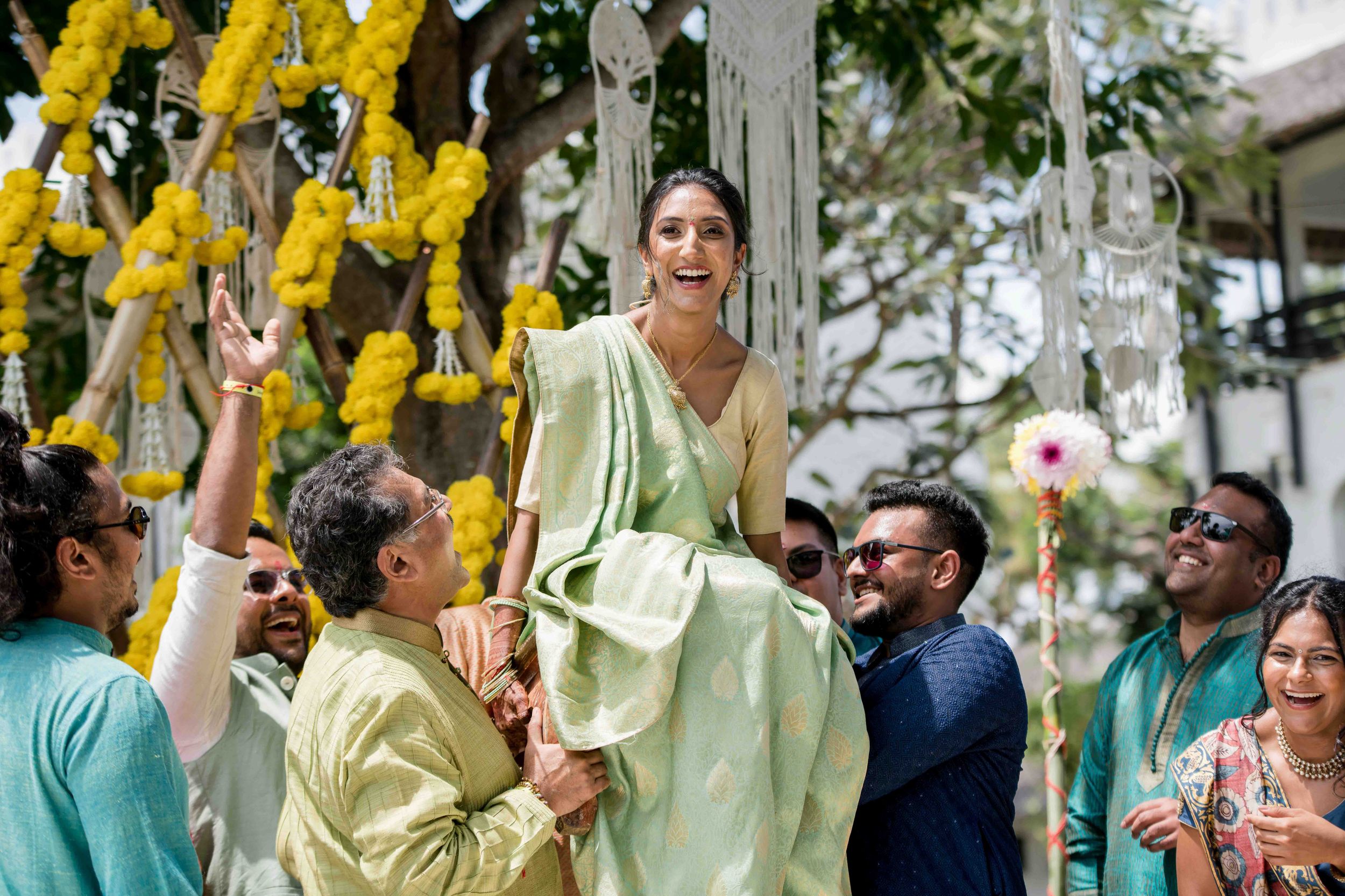 Wedding party members in mint green and yellow attire celebrate during an outdoor ceremony.