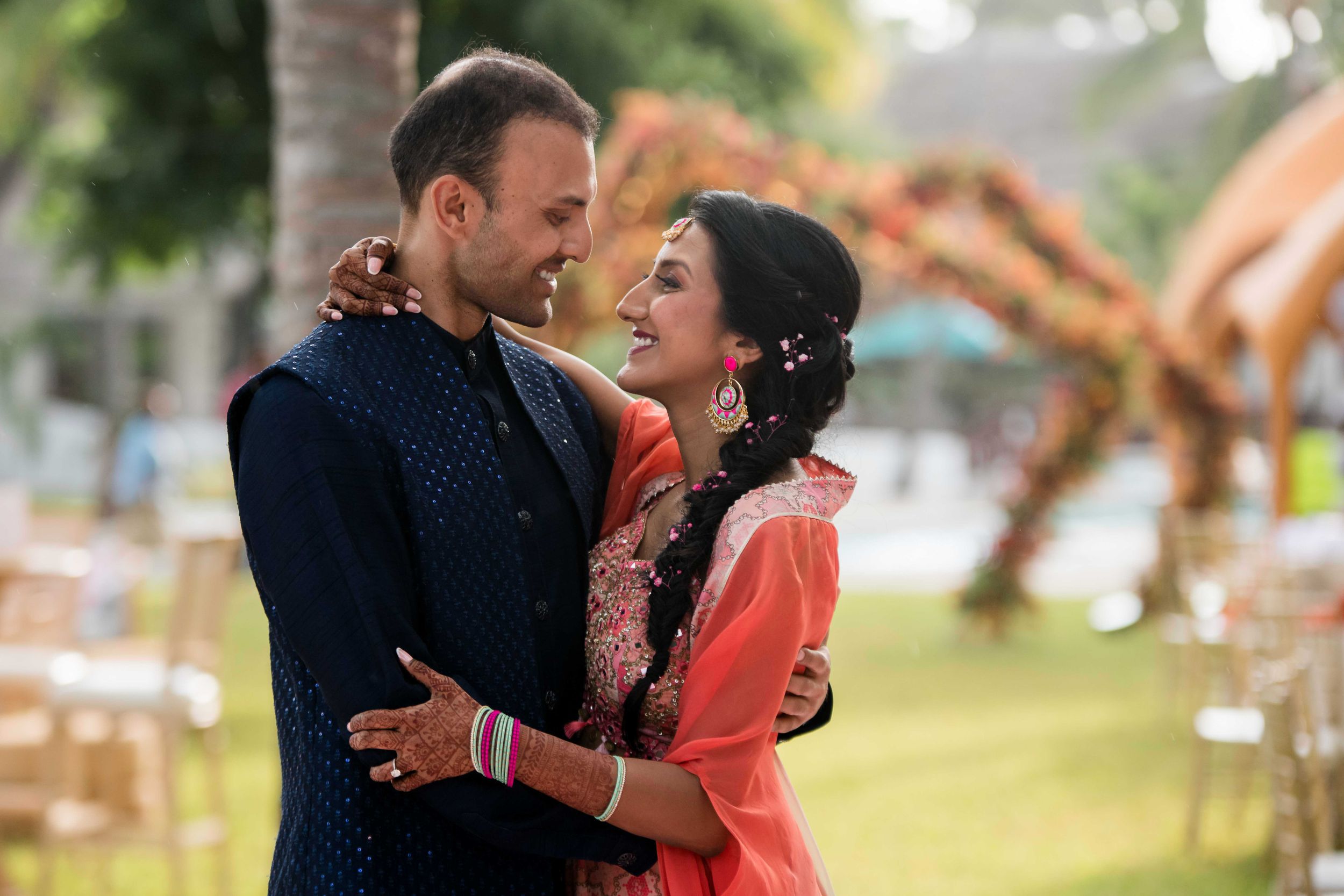 Couple in formal attire holds each other close while dancing in an outdoor setting during golden hour.