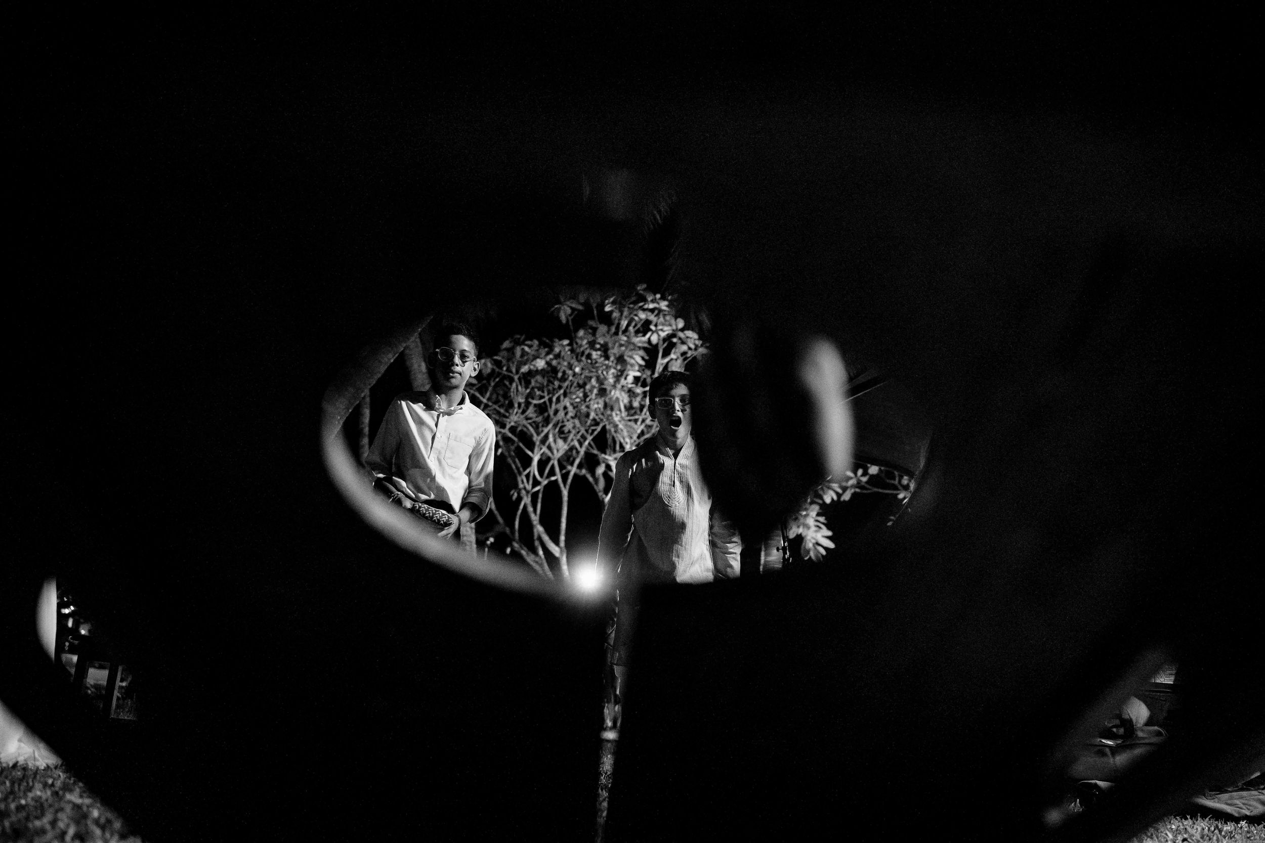 Artistic black and white photograph of a dandelion seed head against a dark background with bokeh effect.