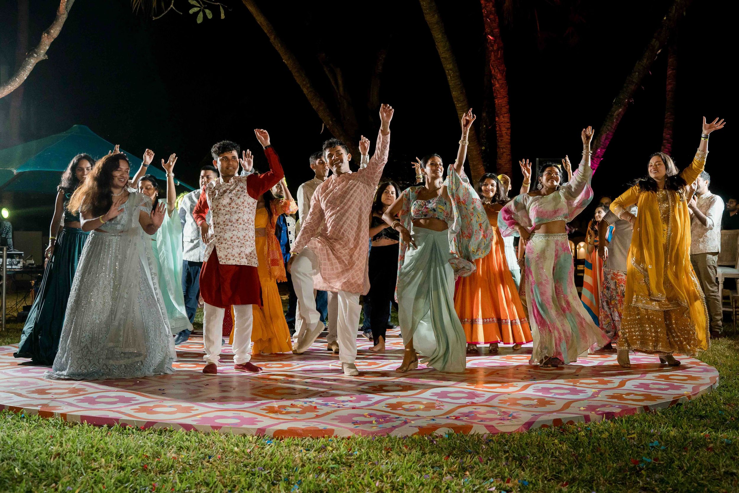 Wedding party members line up in colorful dresses and suits during an outdoor celebration.