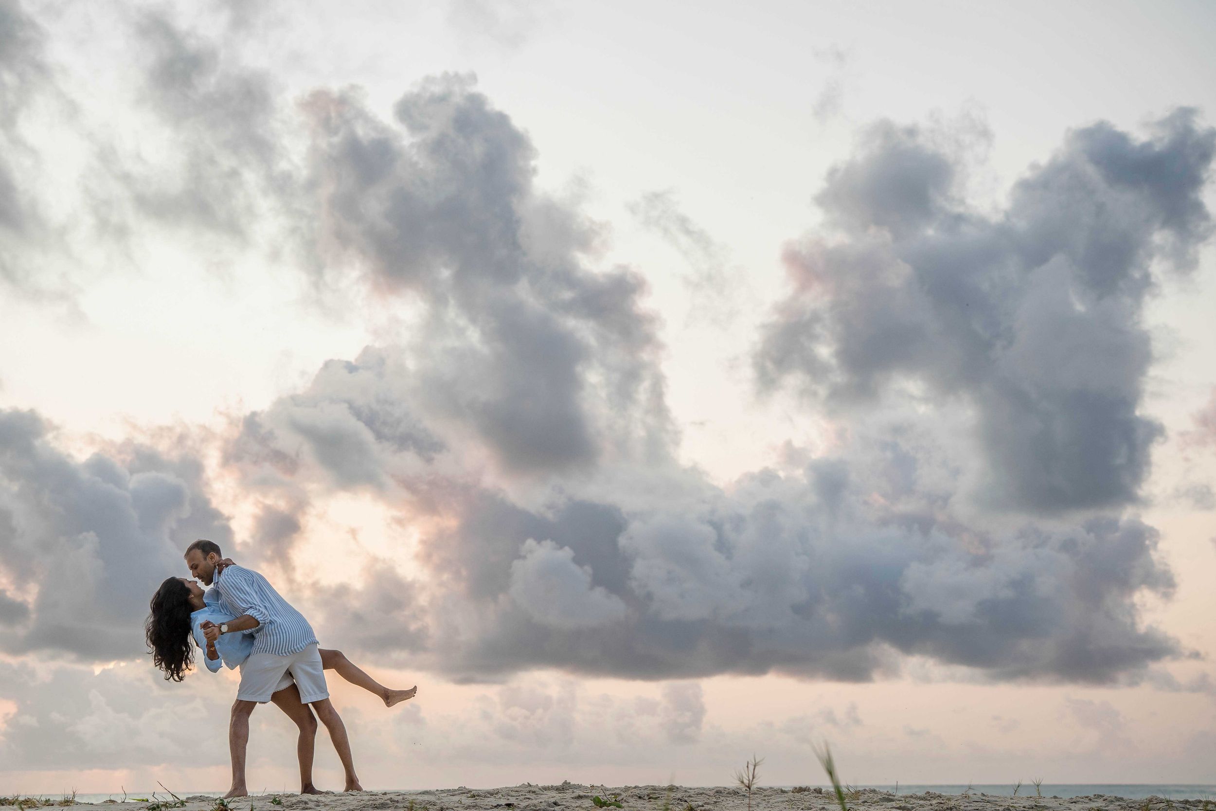 A sequence of seven sunset photos showing acrobatic beach flips against dramatic cloudy skies.