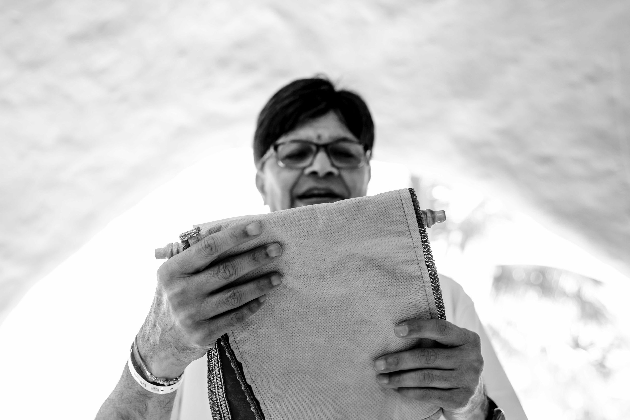 A person reading from papers outdoors captured in black and white with dramatic cloudy sky in the background.