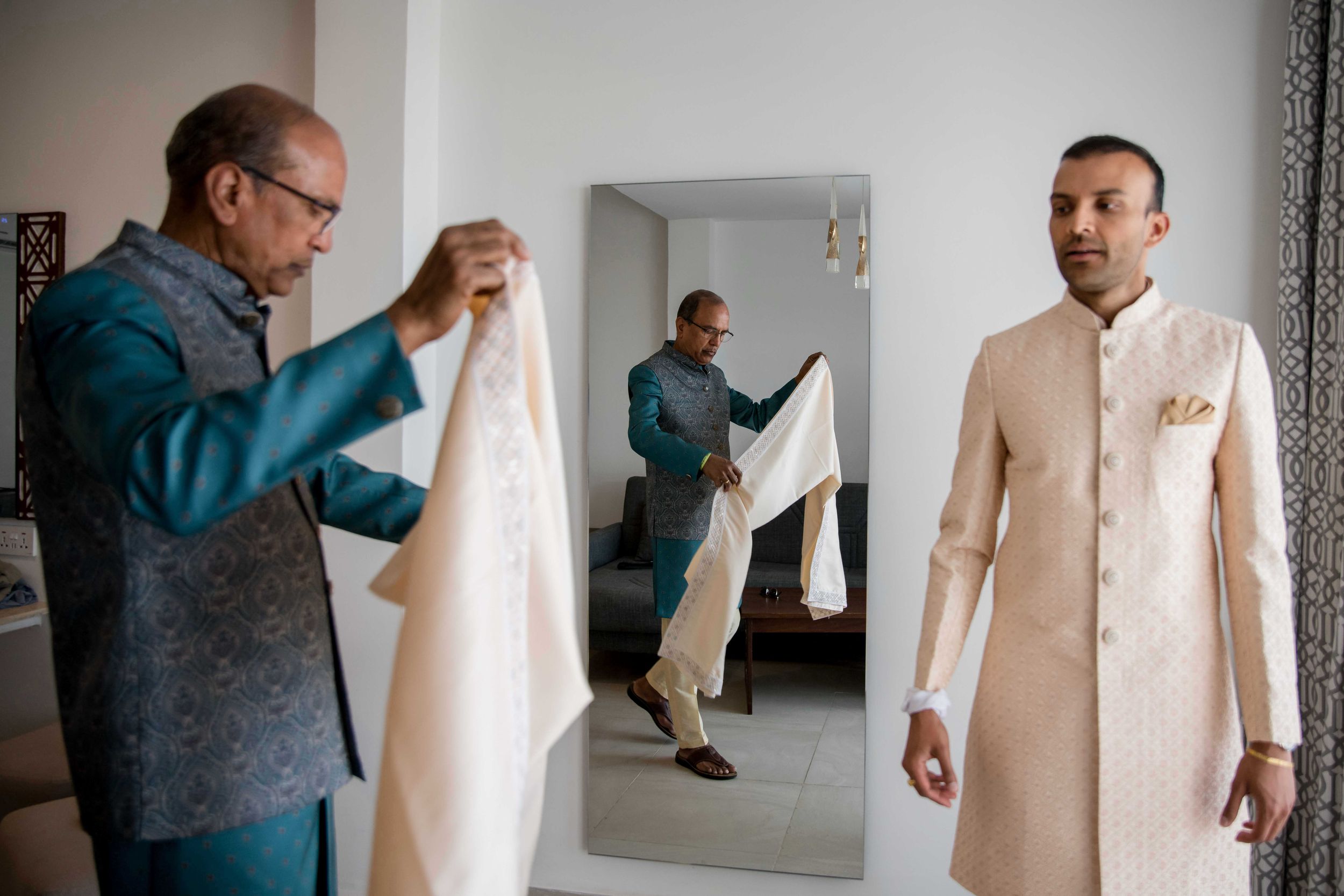 People getting ready for a formal event in a dressing room with light colored attire.