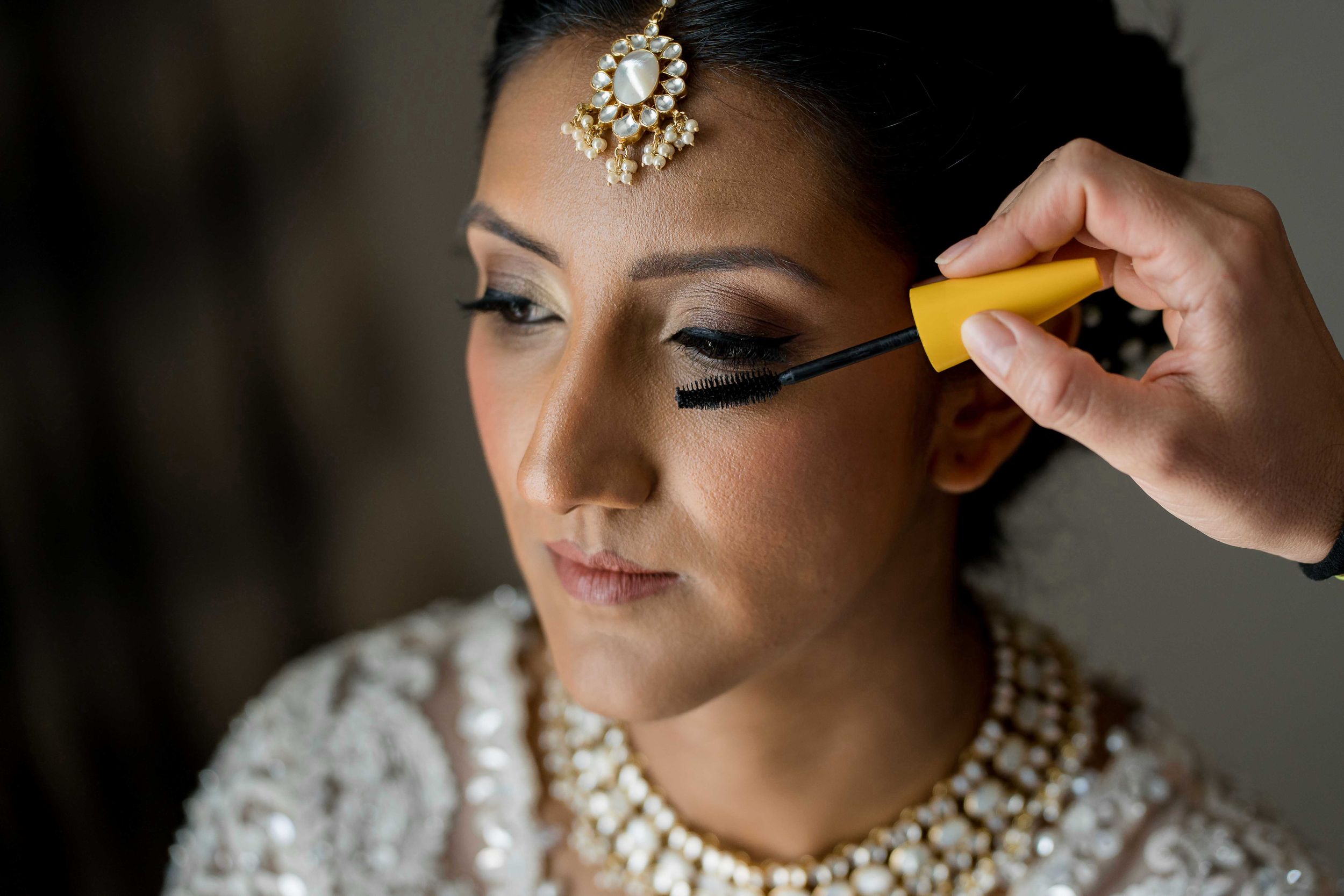 Close-up photos show bridal makeup application with jewelry and eye makeup details in soft natural lighting.