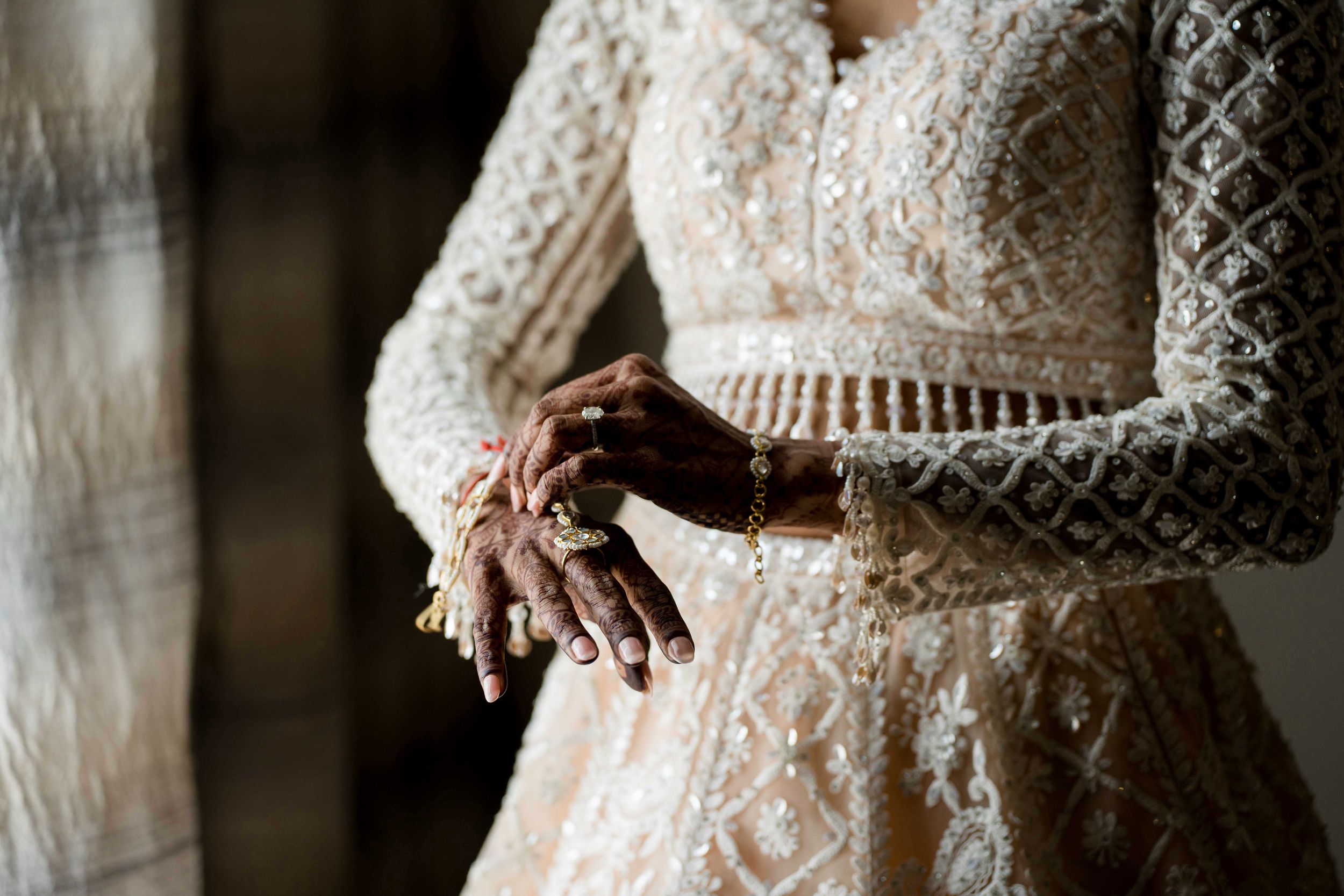 Close-up detail of intricate lace long sleeve wedding dress with delicate beading and pattern work.