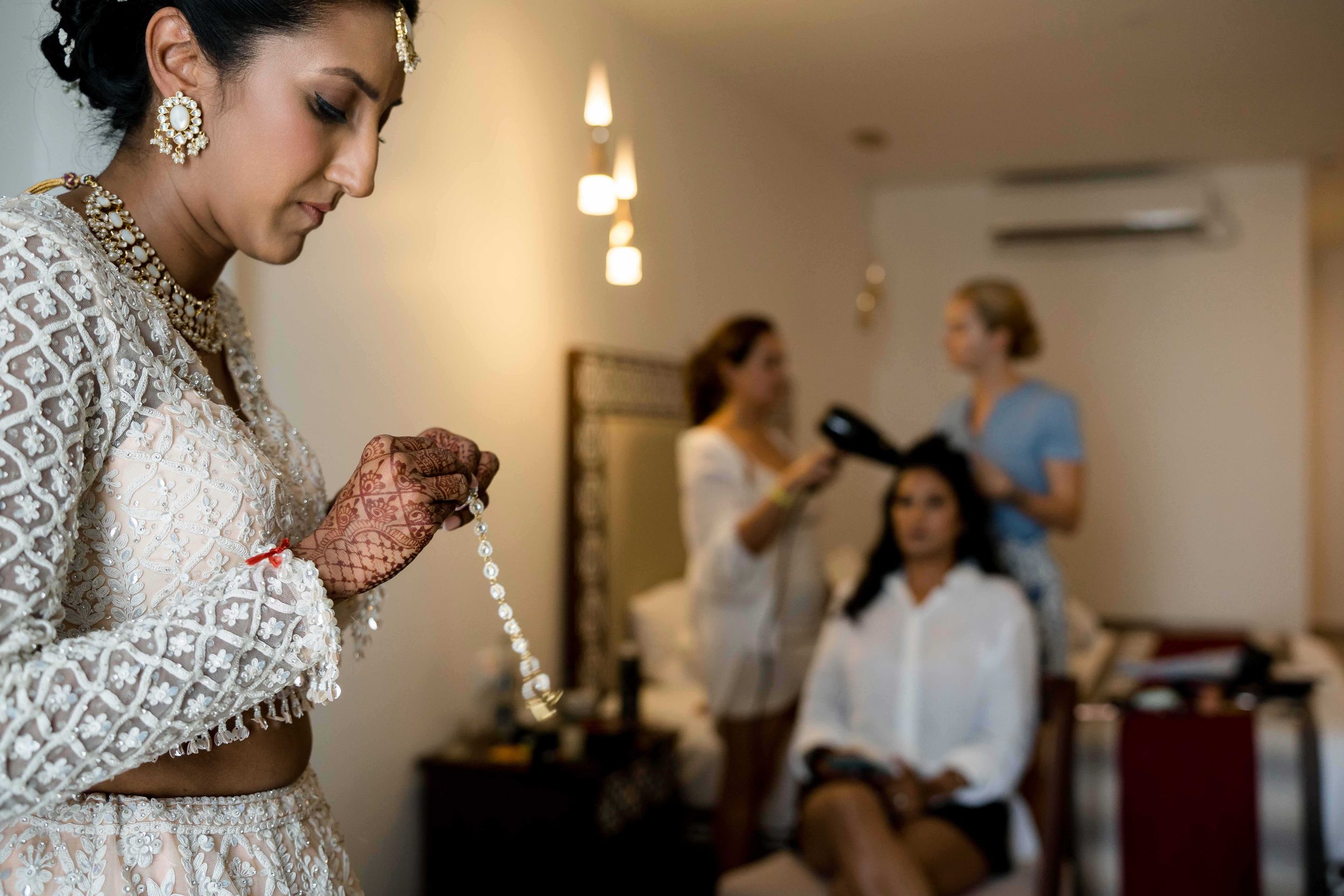 Wedding party getting ready in a bright room while stylists work on hair and makeup preparations for the big day.