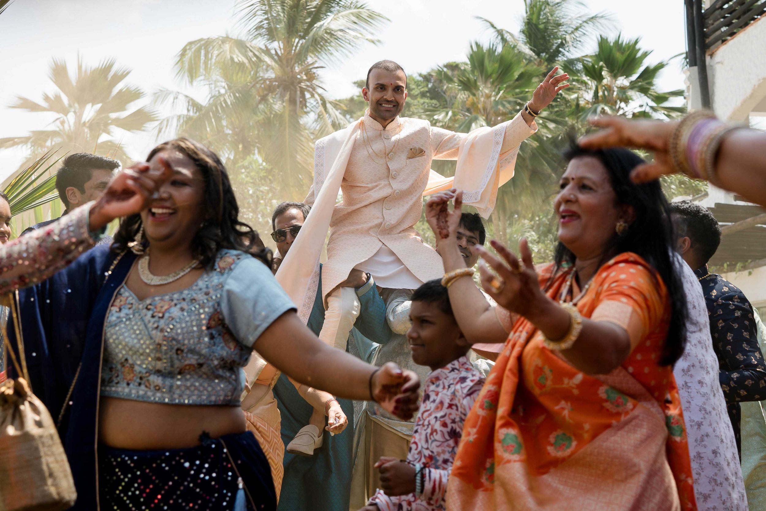 A joyful outdoor celebration with dancing and festivities among palm trees during a lively cultural event.