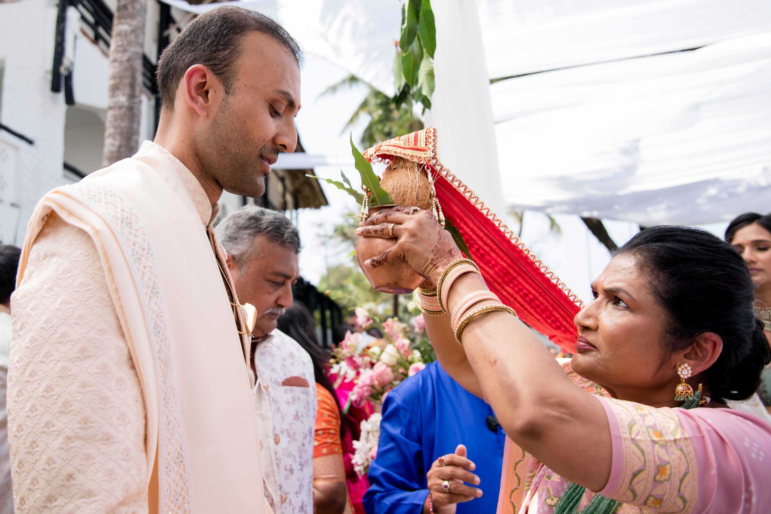 Group of people engaged in festive celebration with traditional Indian attire and rituals at a cultural event.