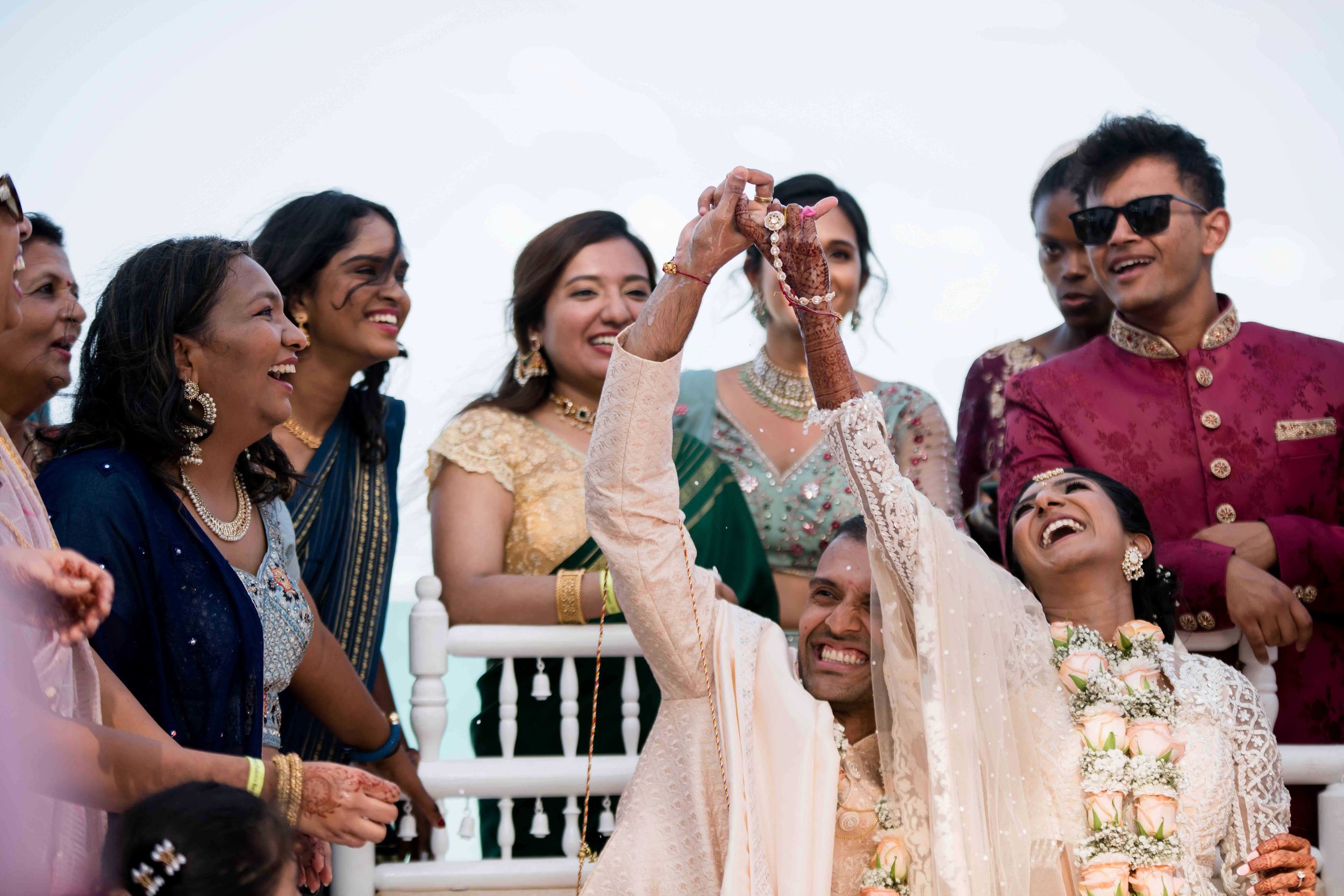 A joyful candid moment of wedding guests laughing together at an outdoor celebration.
