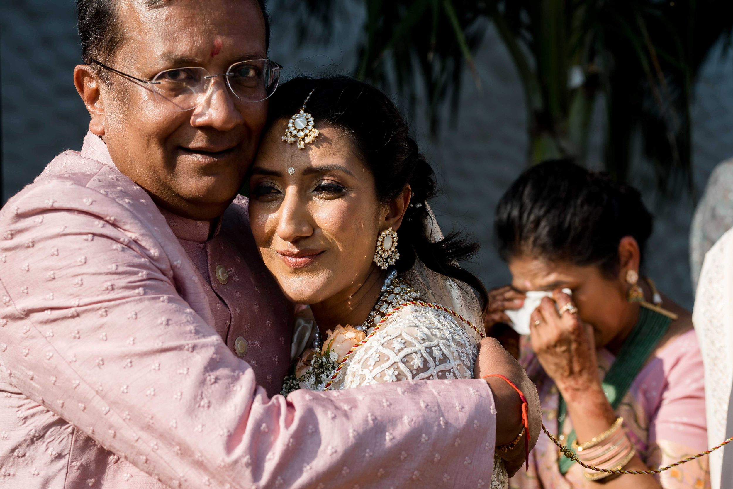 People gather and embrace at a celebration event wearing pink and white clothing.